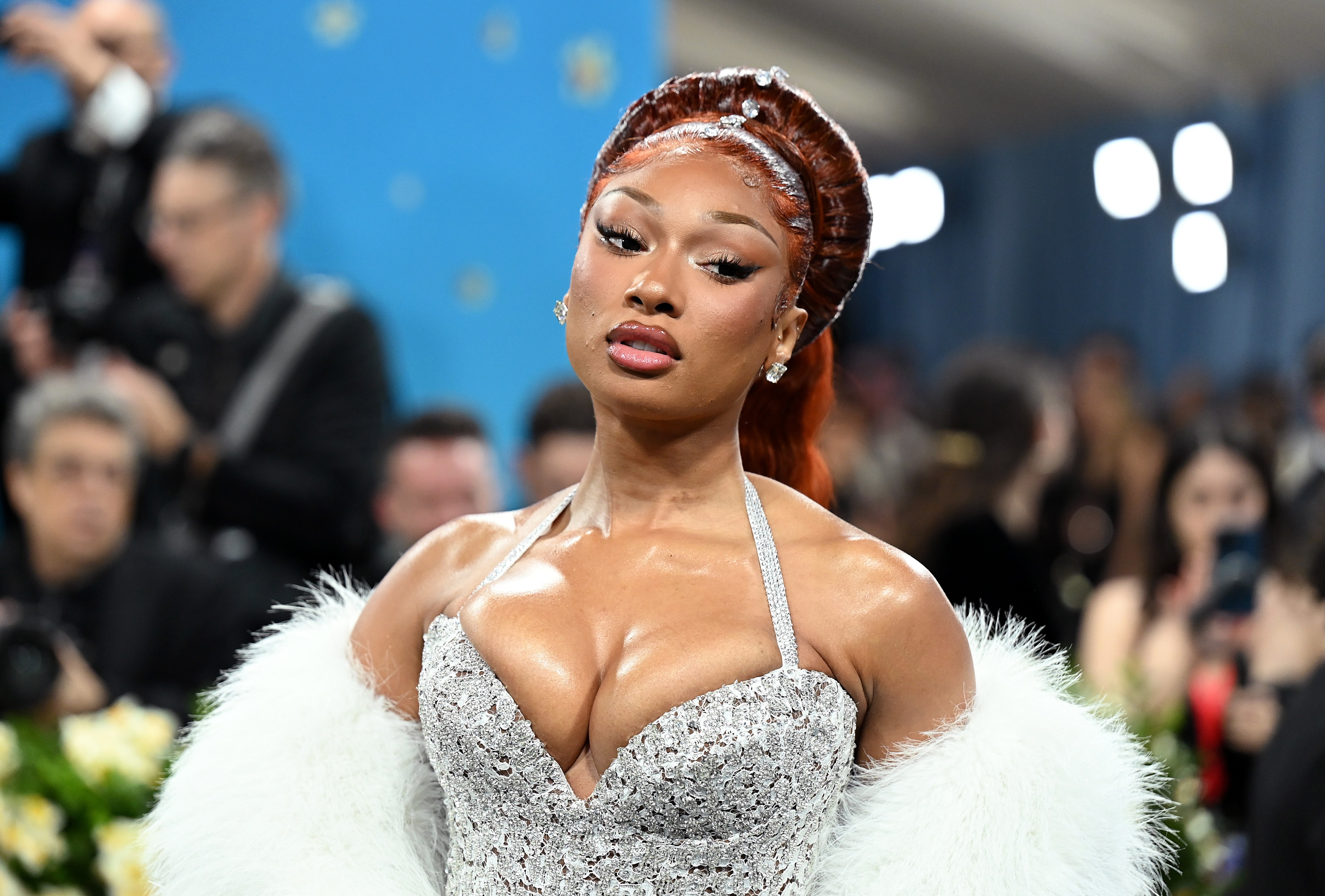 Megan Thee Stallion successful  a sparkly gown with a fur stole poses connected  a reddish  carpet astatine  a ceremonial  event