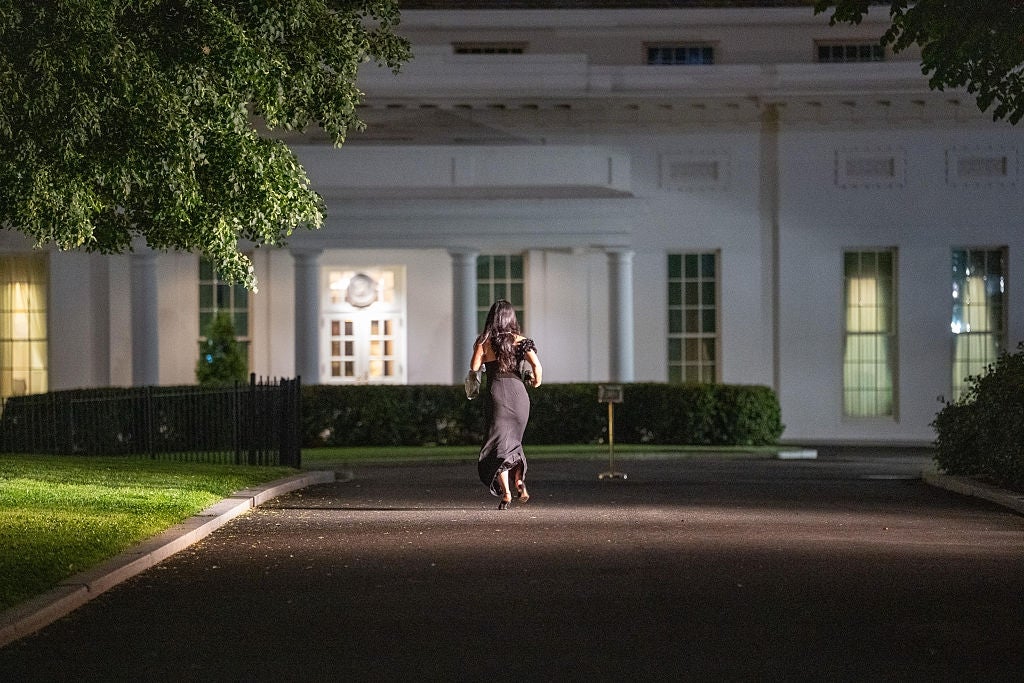 Person walking in evening attire in front of a large, stately building with columns and symmetrical windows