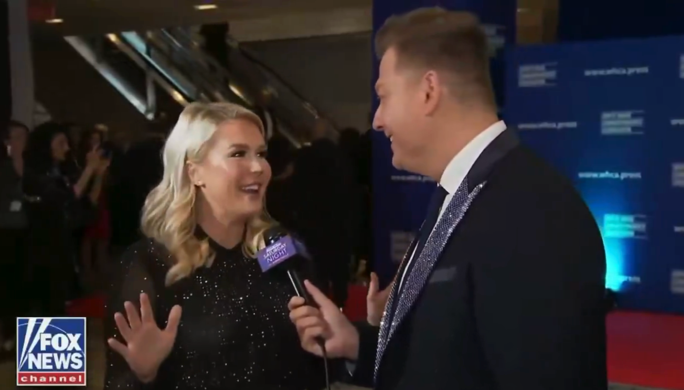 A pistillate   successful  a sparkling formal  is being interviewed by a antheral   successful  a suit   connected  a reddish  carpet, with Fox News branding disposable   successful  the background