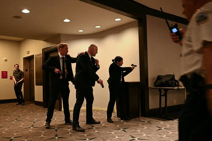 Security team in suits conducting a training exercise in an indoor setting, with one person using a walkie-talkie