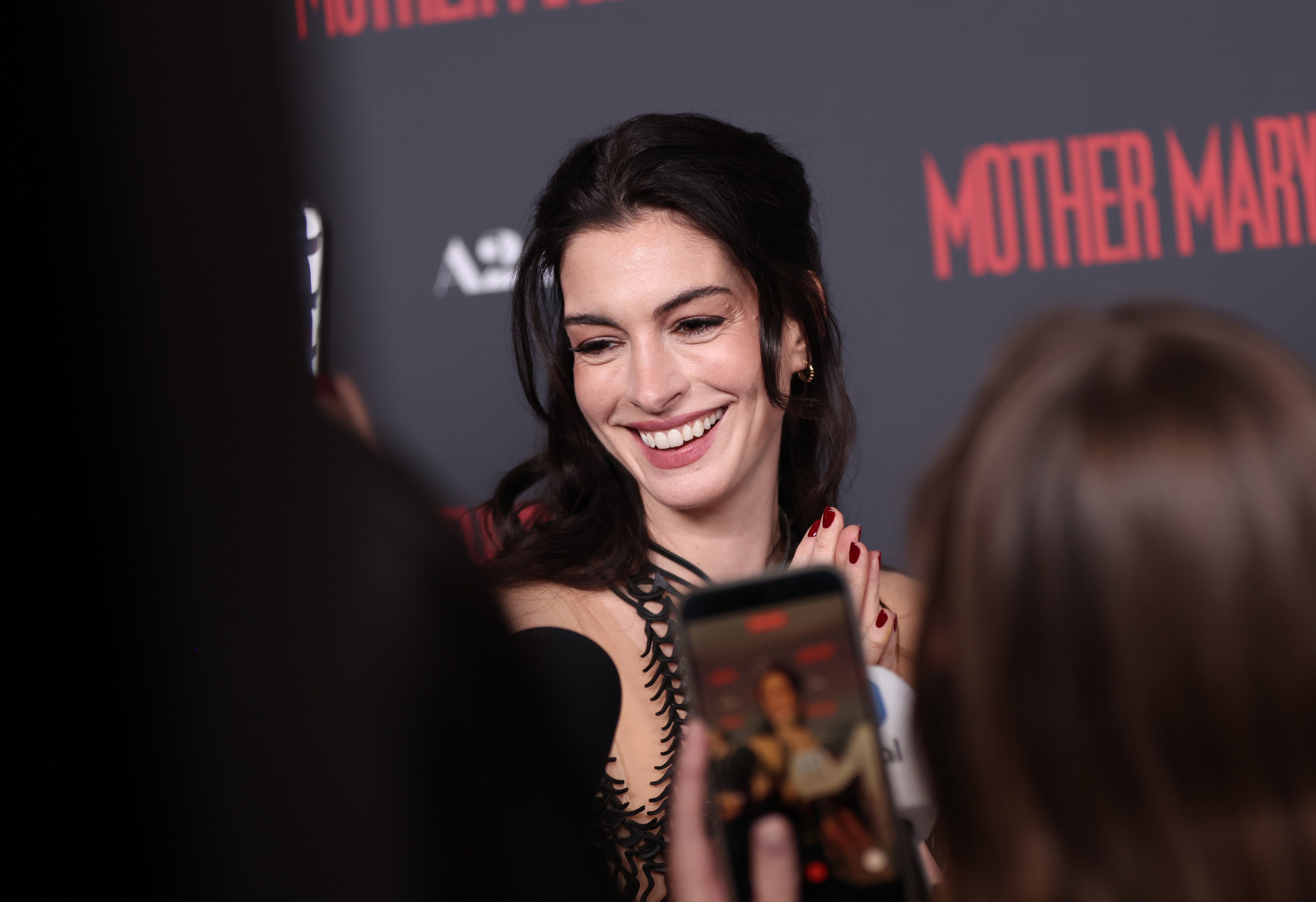 Anne Hathaway connected  the reddish  carpet, smiling and wearing a stylish formal  with intricate design, portion    surrounded by media and fans taking photos