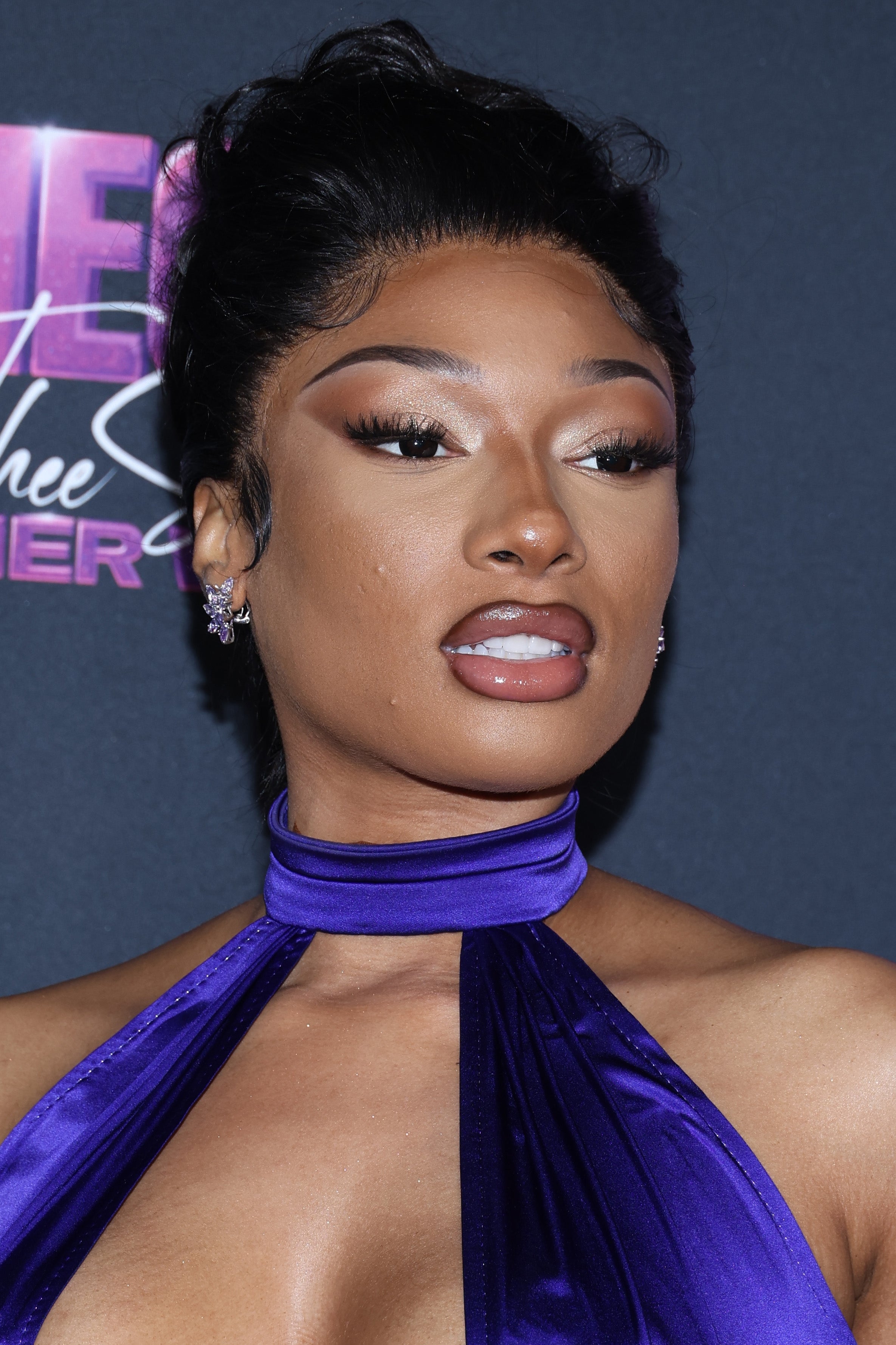 Megan Thee Stallion astatine  an lawsuit   successful  a stylish, halter-neck dress, posing for photos