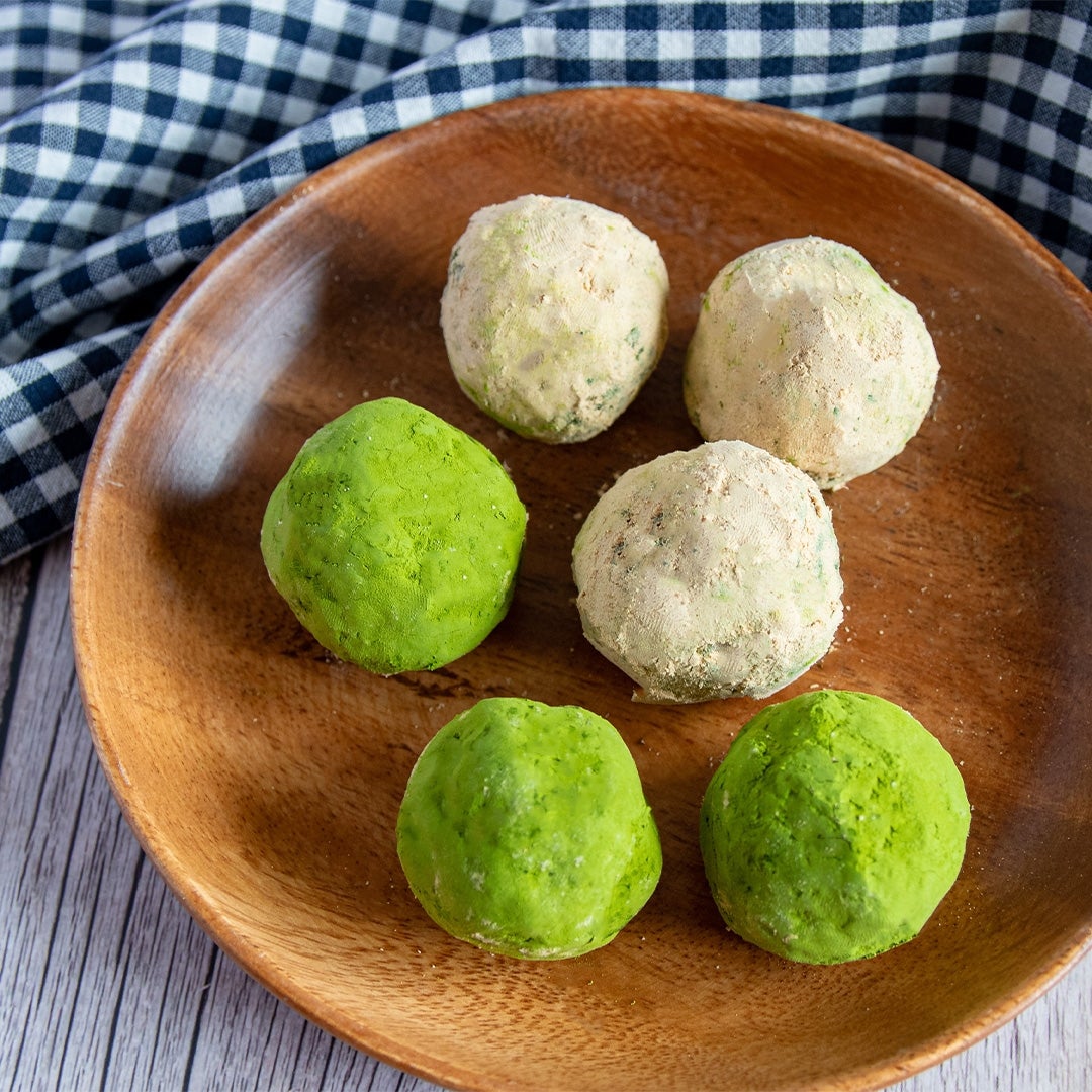 木製のプレートに抹茶ときなこの和菓子ボールが6個並んでいる。チェック柄の布が背景にある。