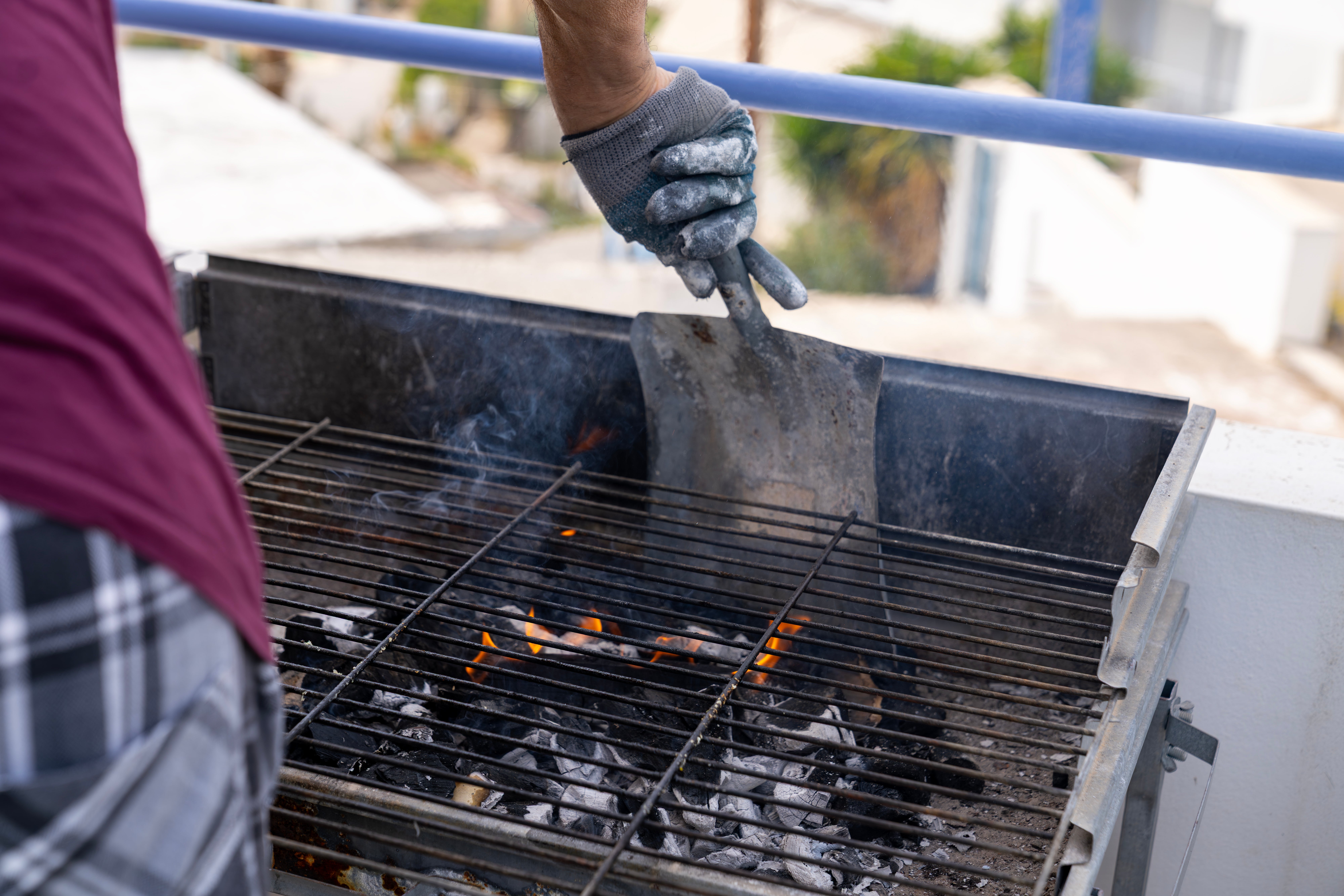 Person grilling nutrient  outdoors, utilizing a metallic  cooking instrumentality   to set  coals connected  a barbecue grill