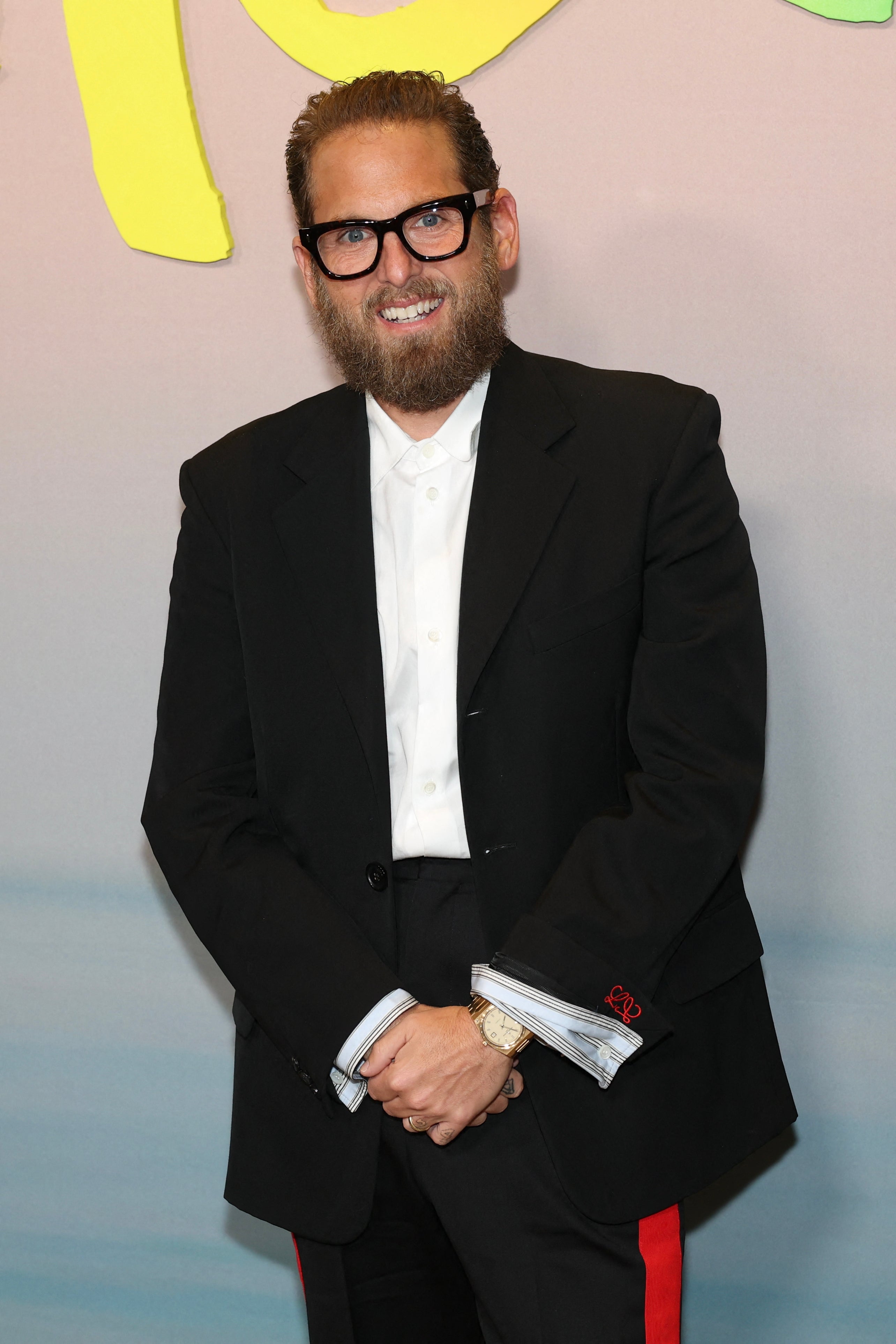 Person successful  a stylish achromatic  suit   with reddish  accents and glasses astatine  a nationalist   event