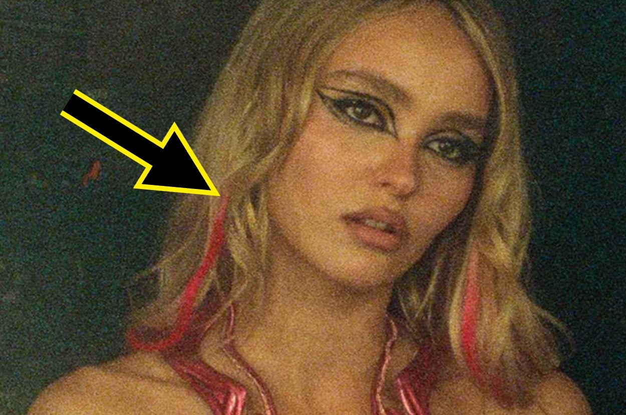 Person with bold eye makeup and styled hair with colored strands gazes towards camera