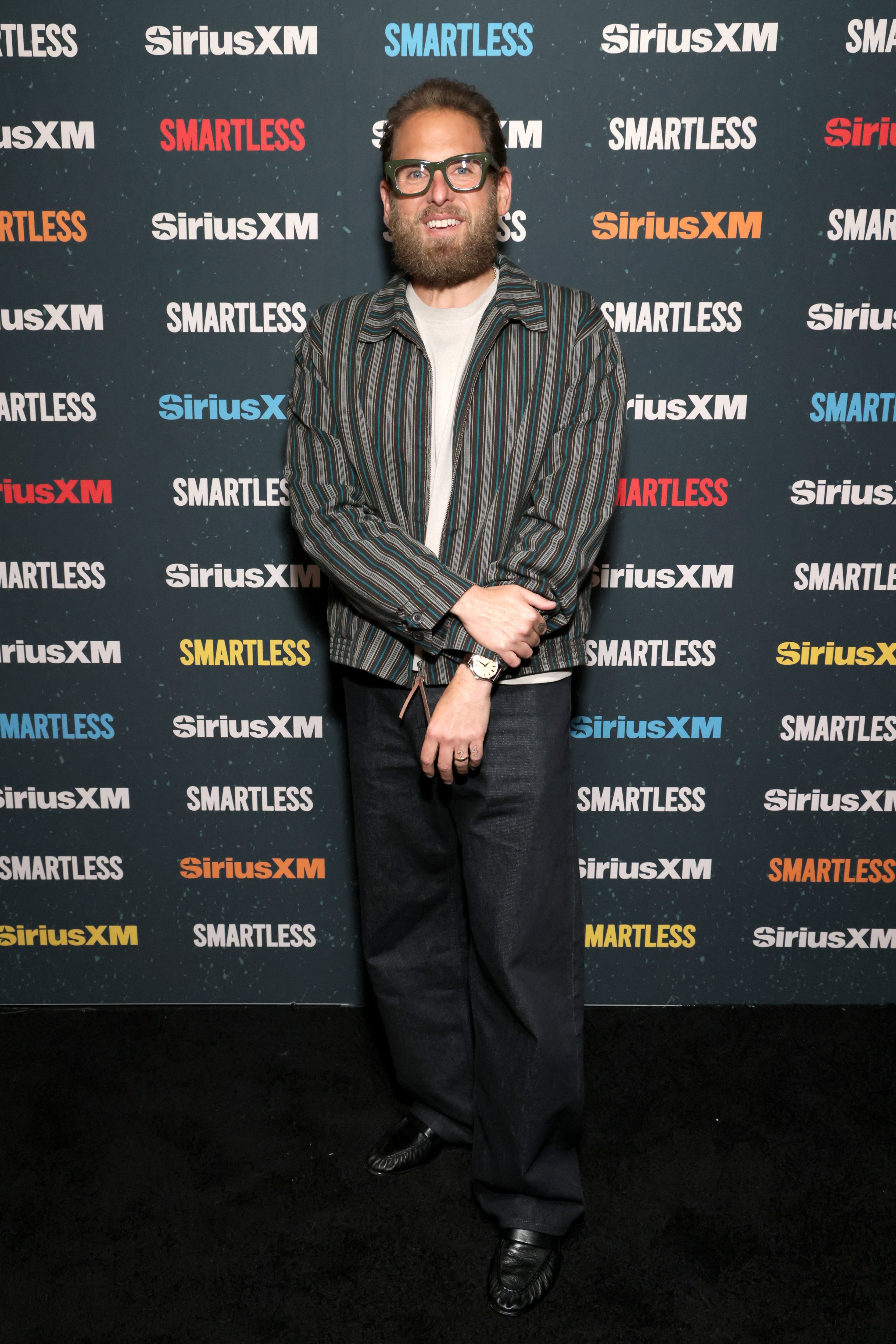 Person successful  a striped overgarment   and casual outfit posing astatine  a SiriusXM lawsuit   backdrop