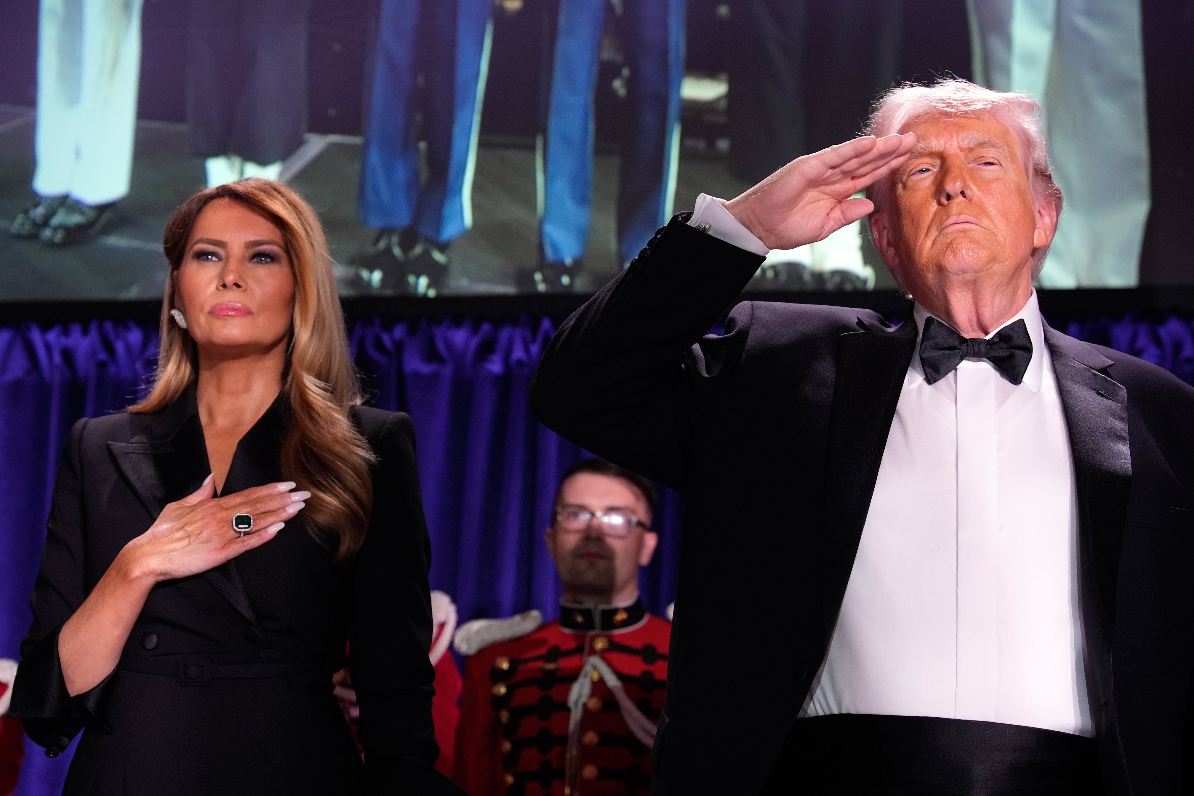 Two radical   successful  ceremonial  attire, with 1  saluting and the different   placing a manus  connected  their chest, basal   astatine  an lawsuit   with a uniformed idiosyncratic   successful  the background