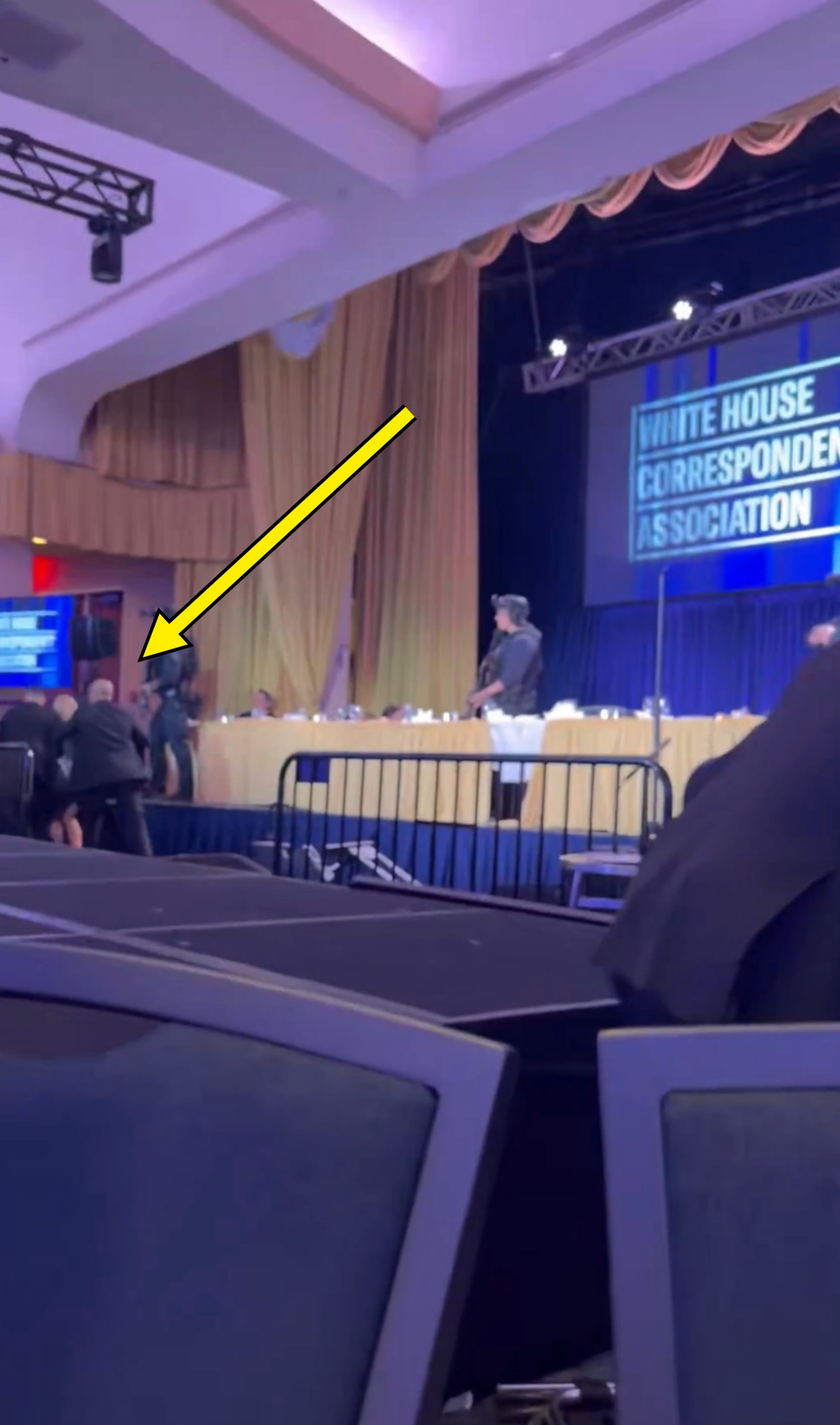 Event hallway  with a "White House Correspondents' Association" banner, radical   connected  stage, assemblage  seated
