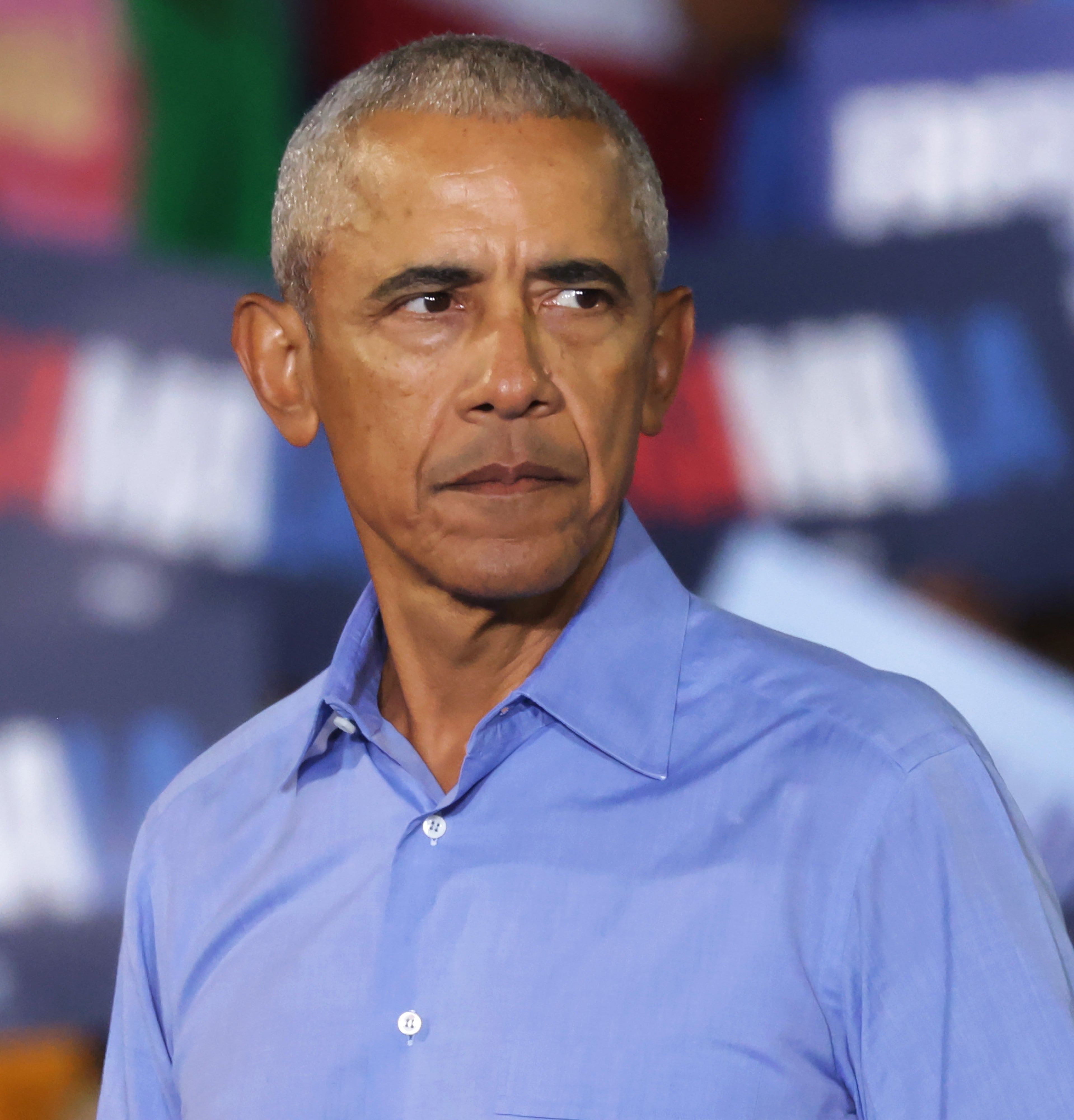 A idiosyncratic   successful  a bluish  garment  stands successful  beforehand   of a assemblage  holding signs with letters