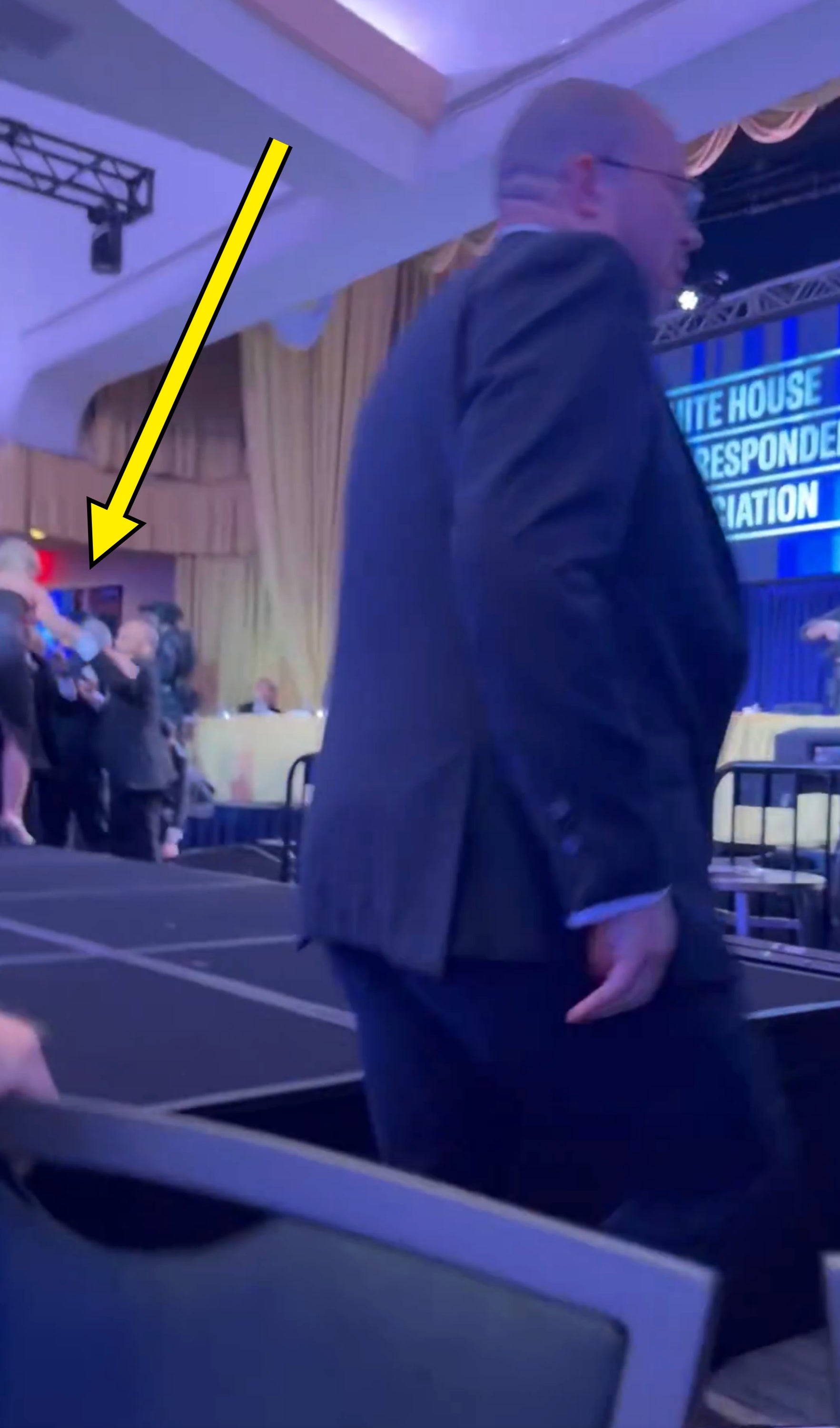 Person successful  a suit   walking connected  signifier    astatine  a ceremonial  lawsuit   with "White House Correspondents' Association" motion   successful  the background