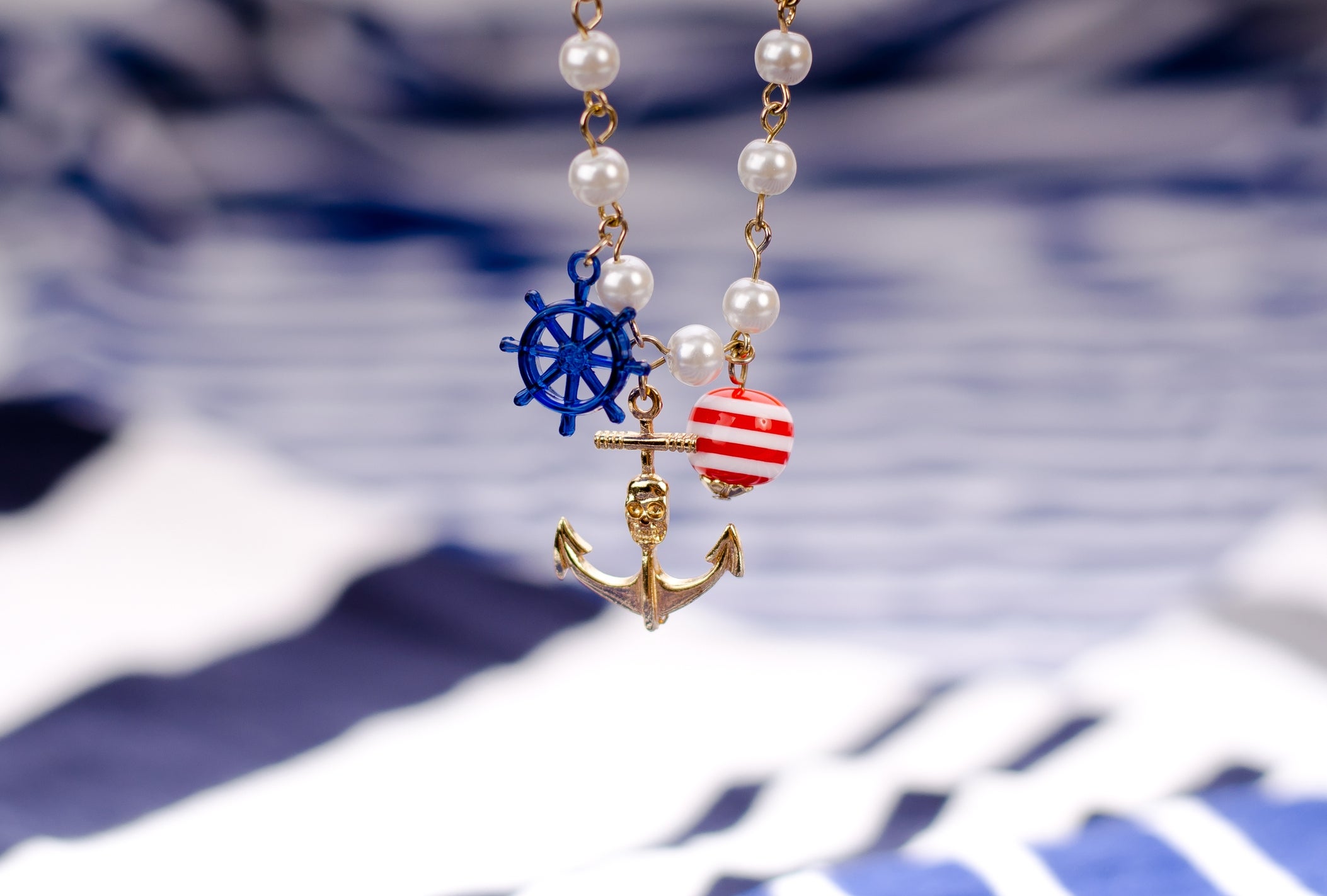 Close-up of a necklace with pearl concatenation  featuring anchor, helm, and striped bead charms