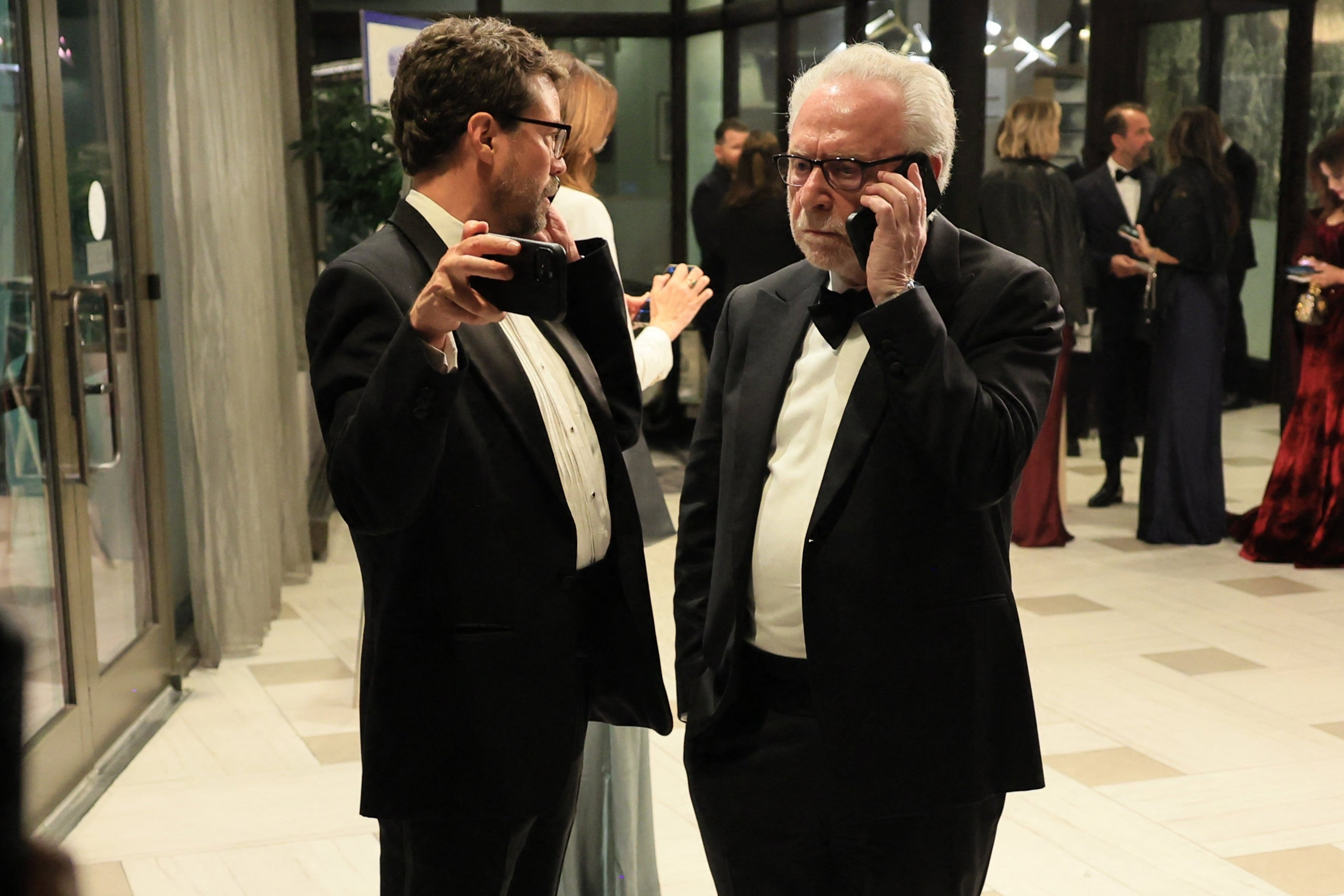 People successful  evening deterioration  mingle and instrumentality     photos astatine  a ceremonial  lawsuit   entrance, including a ballroom and overgarment  cheque  signs disposable   successful  the background