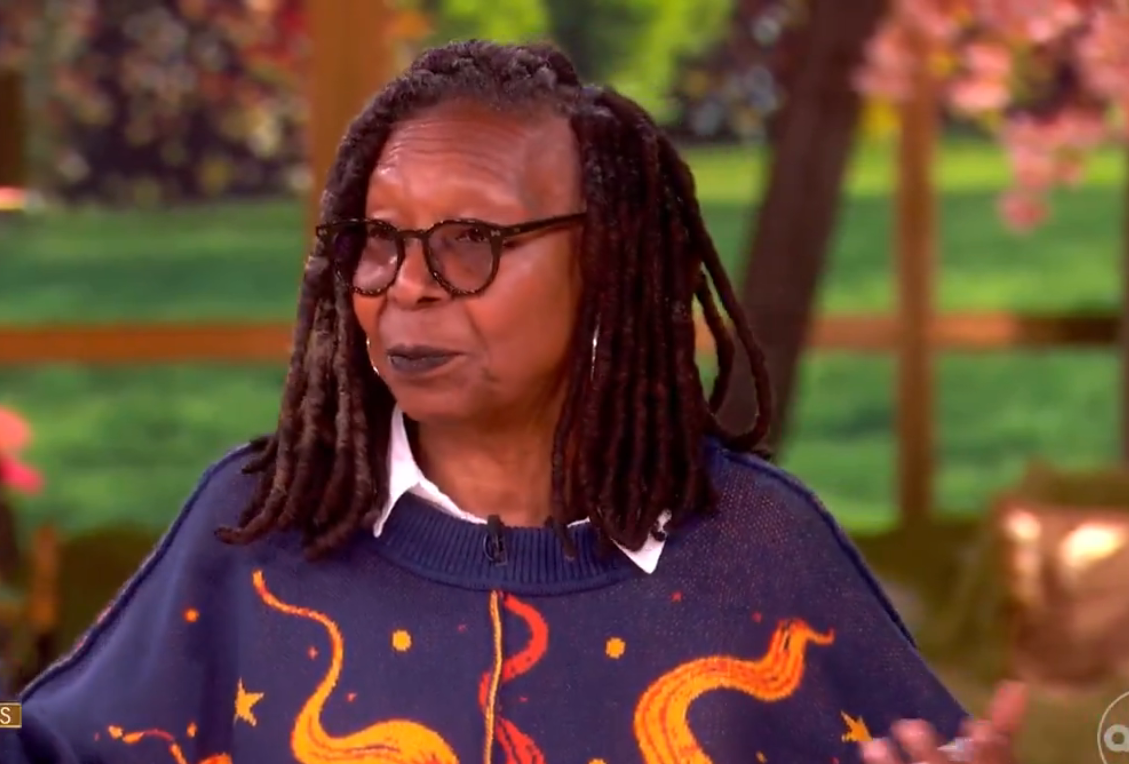 Person speaking connected  a speech   amusement   set, wearing glasses and a sweater with abstract designs