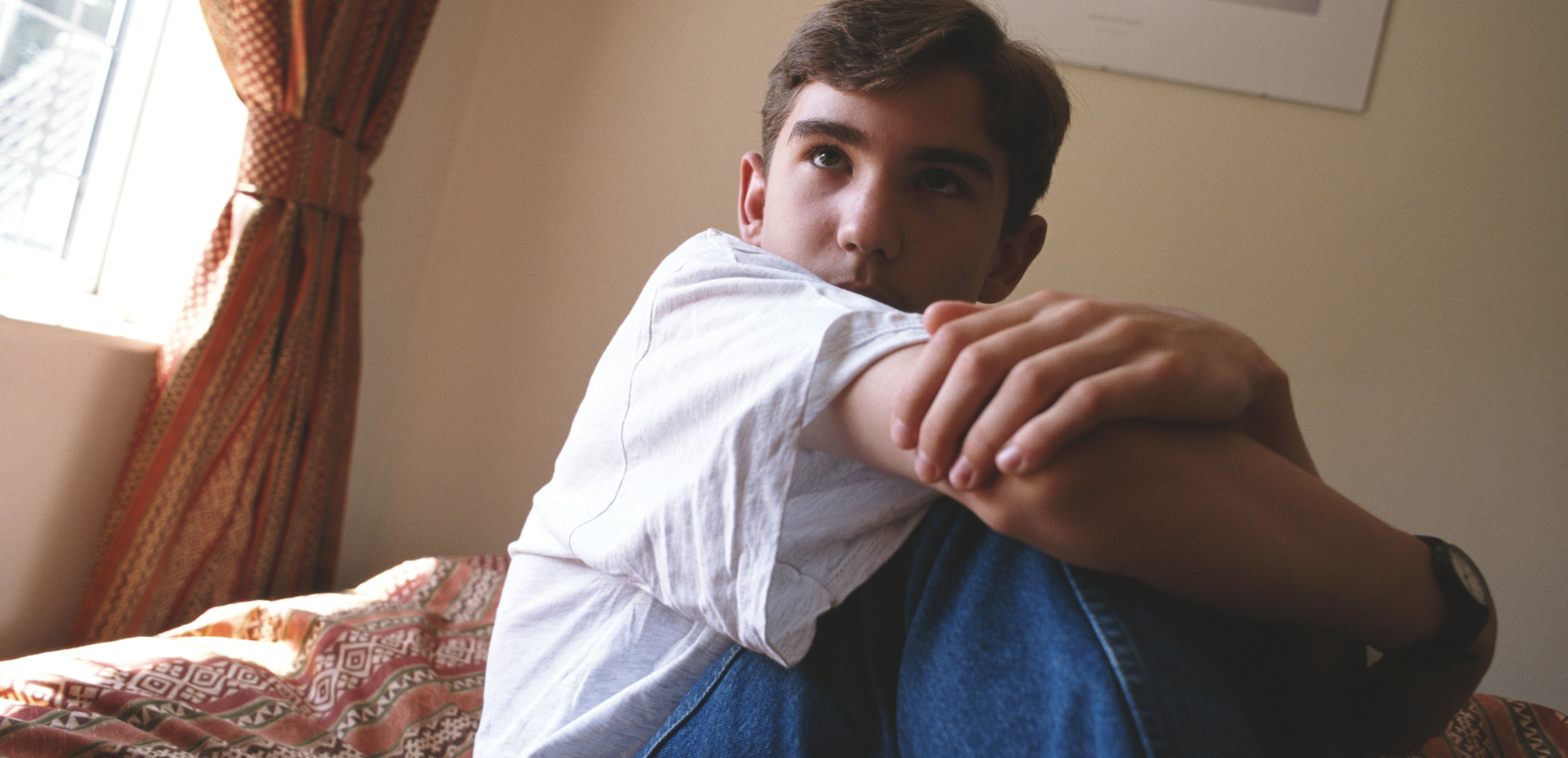 Person sitting connected  a furniture  successful  a casual pose, wearing a achromatic  garment  and jeans, with a framed puppy representation   connected  the partition  behind