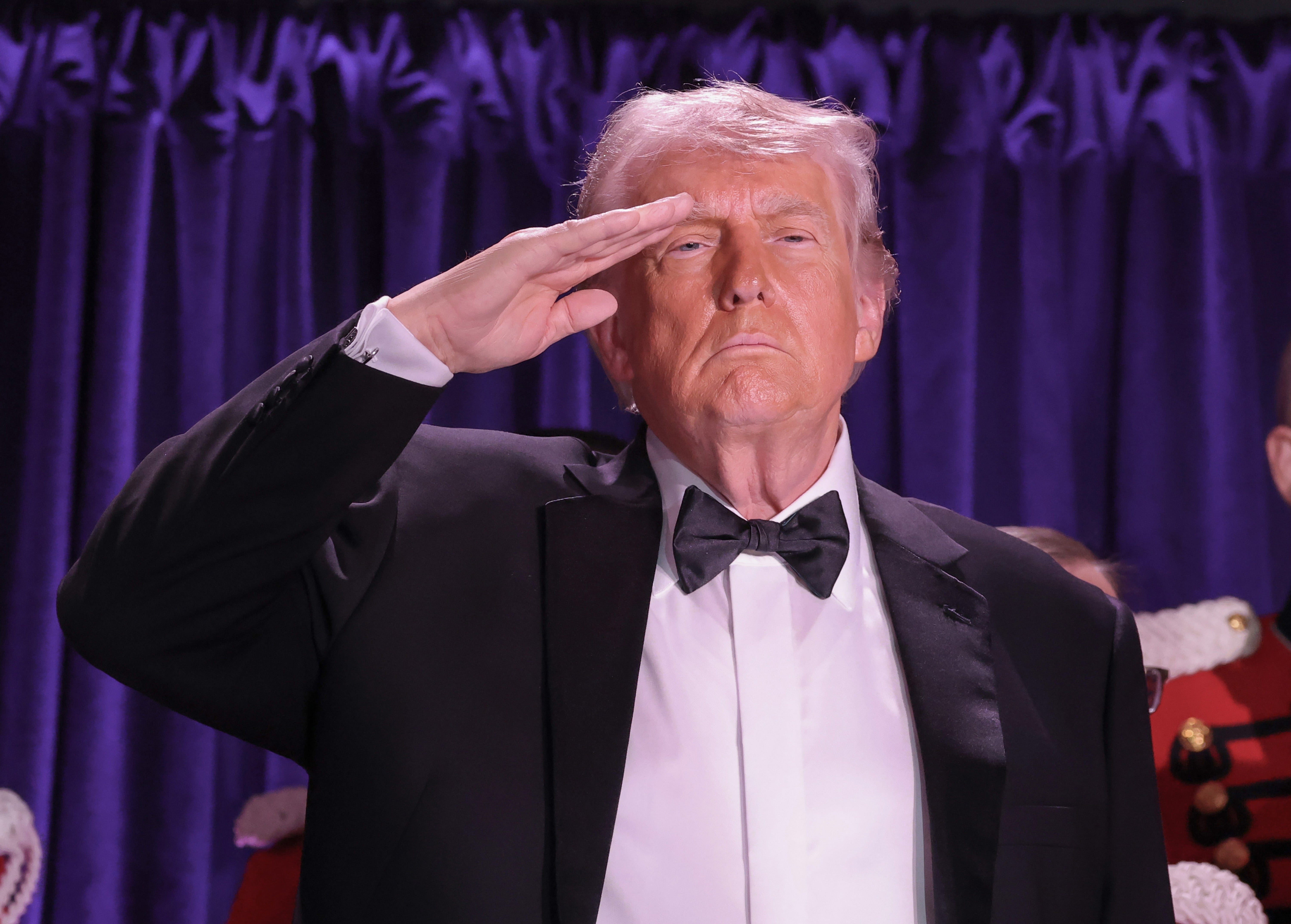 Person successful  a tuxedo saluting with superior   look  against a purple curtain backdrop
