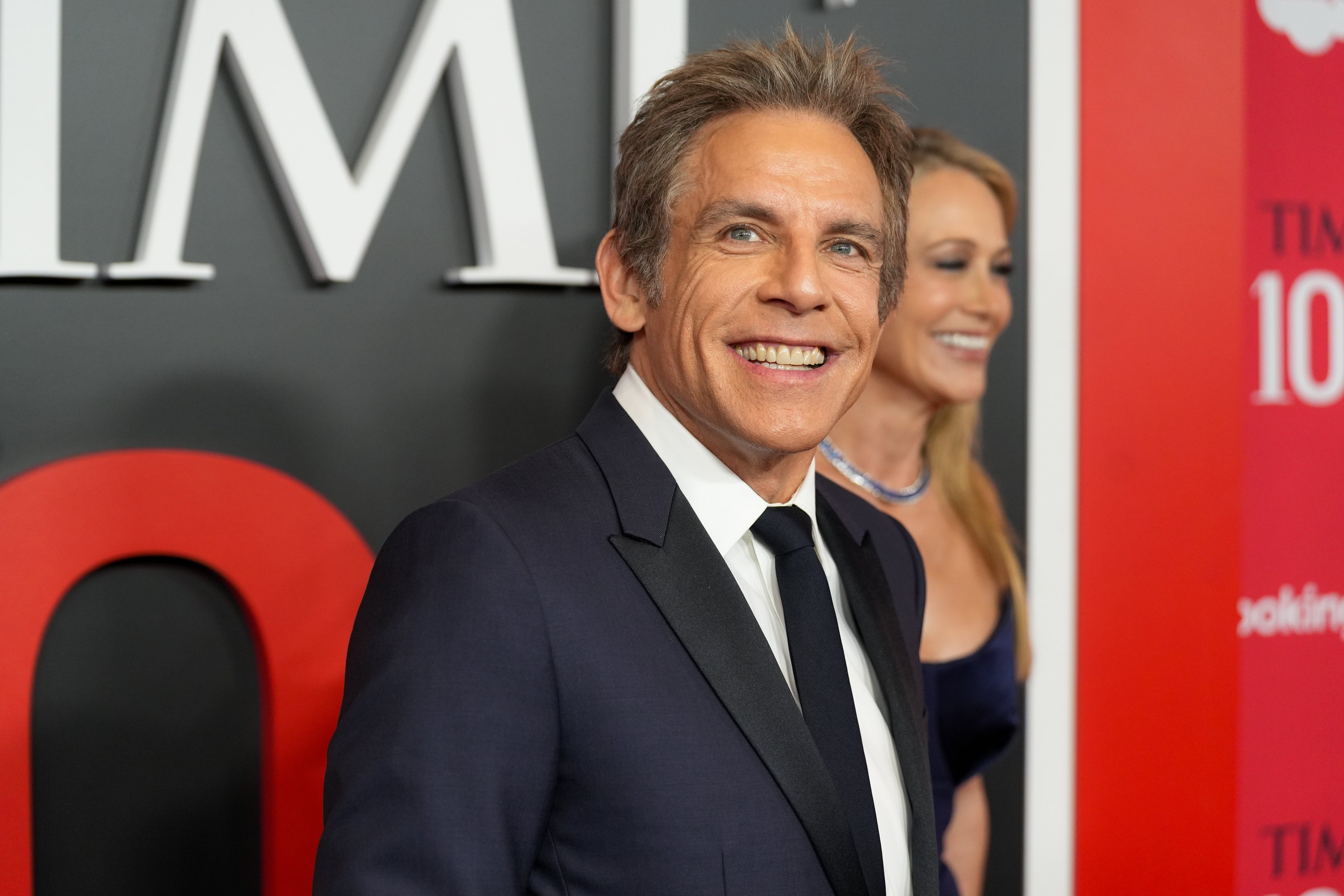 A idiosyncratic   astatine  an lawsuit   wearing a classical  suit   and tie, smiling for the cameras, with a step-and-repeat backdrop down  them