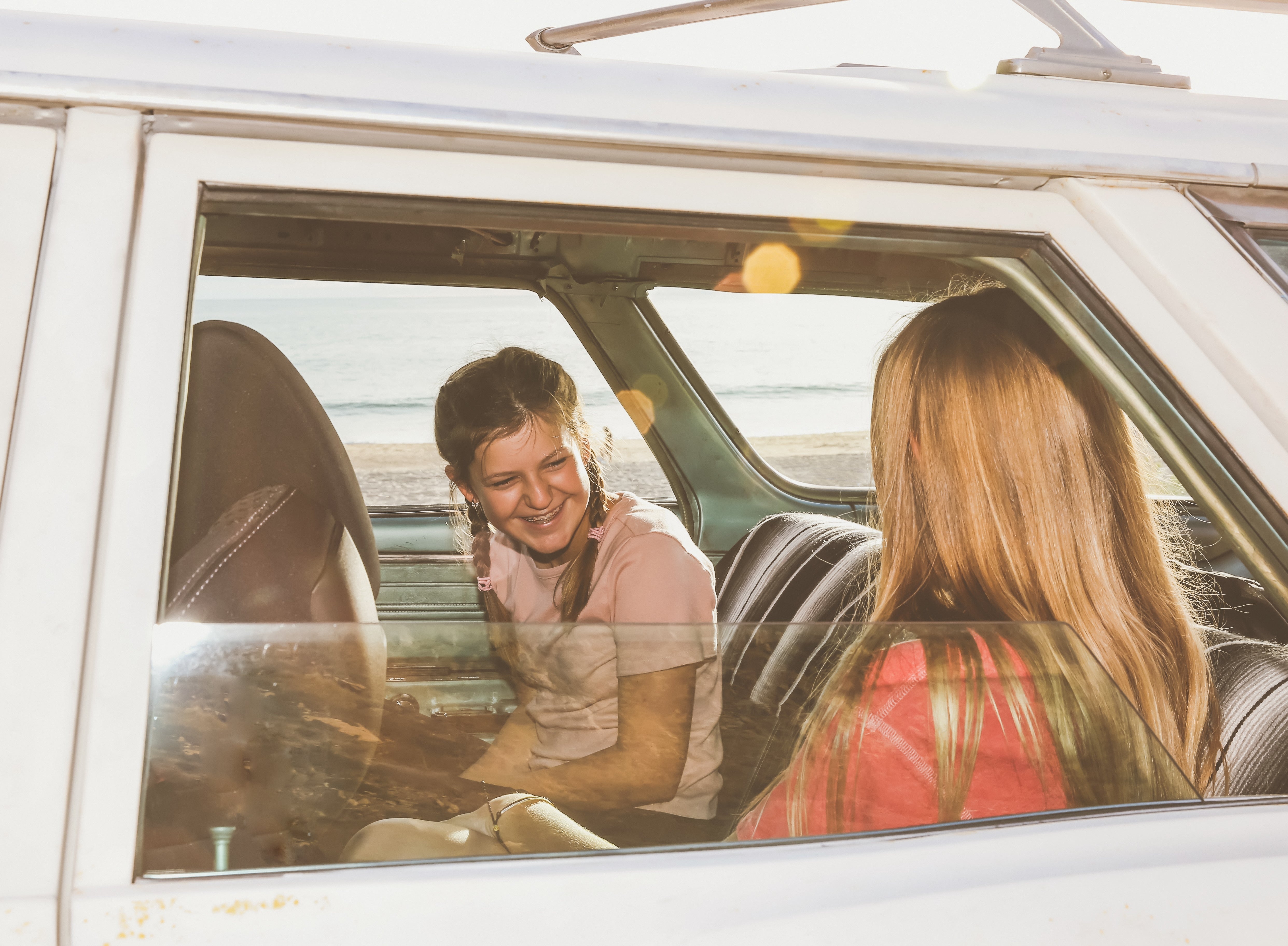 Two radical   beryllium   successful  a car   by the beach, smiling astatine  each   different   done  the window