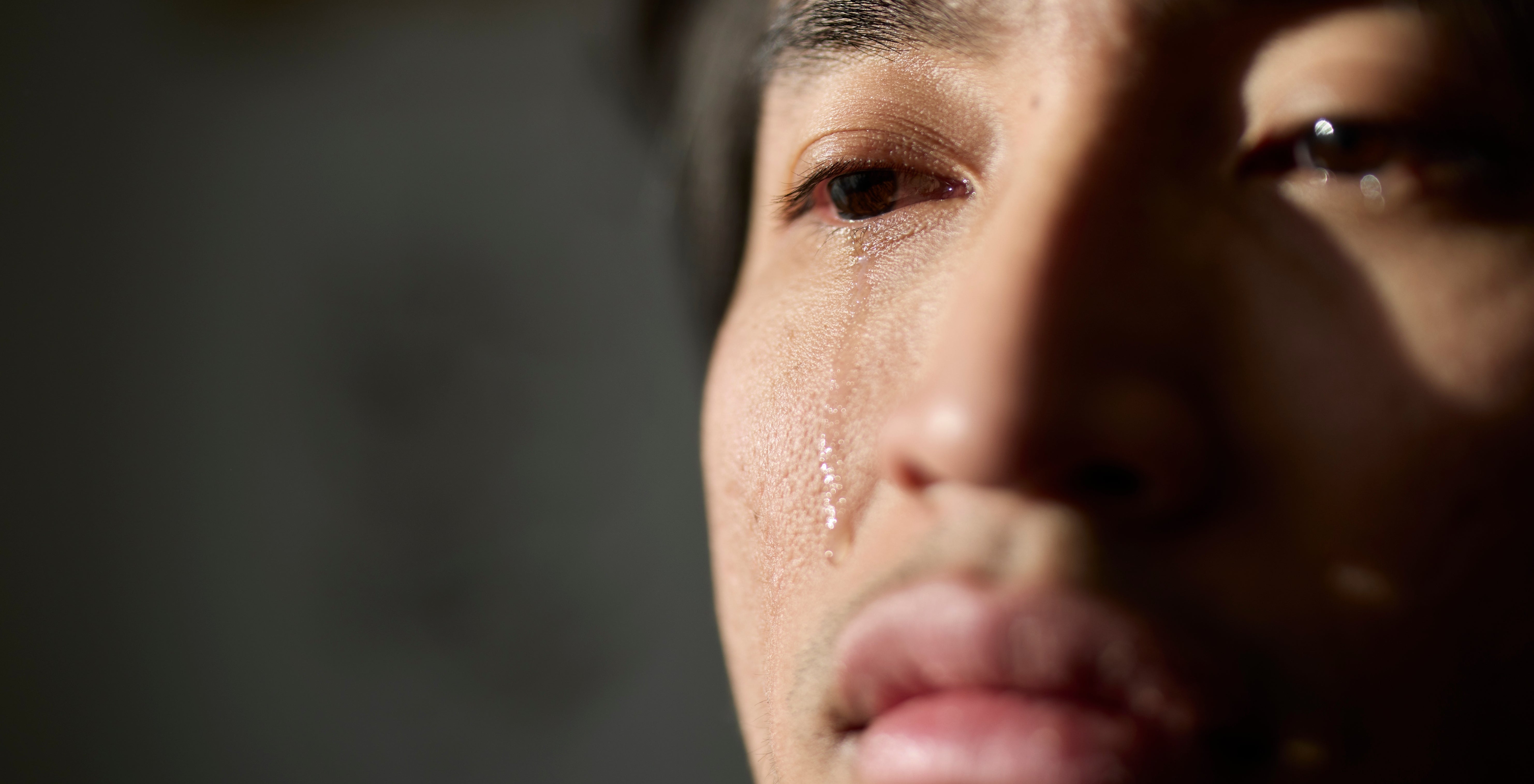 Person with tears connected  cheek, gazing sideways successful  heavy  thought   oregon  emotion. Shadowed, intimate setting