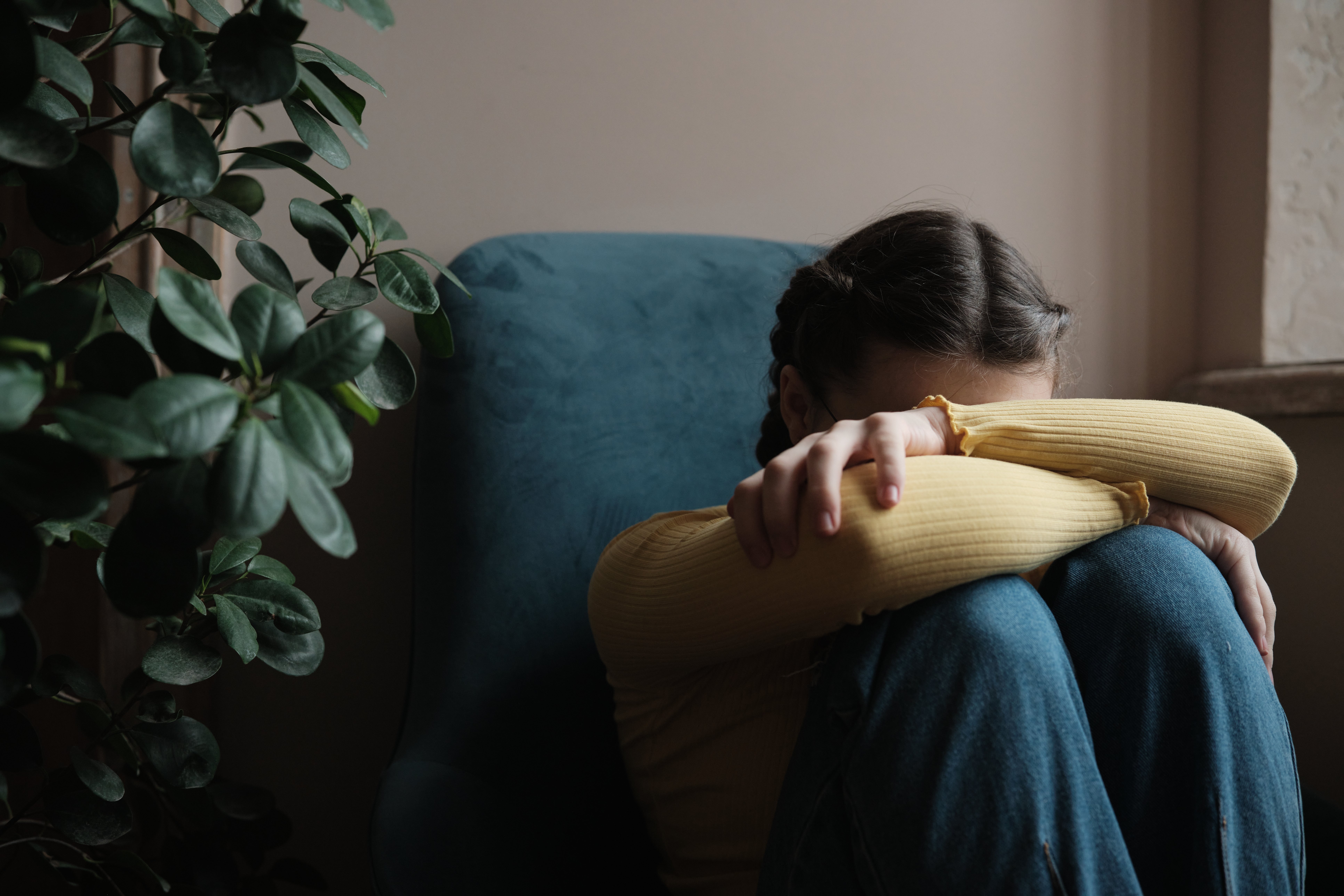 Person sitting connected  a chair, resting their caput  connected  their arms, which are crossed implicit    their knees, successful  a contemplative oregon  fatigued pose