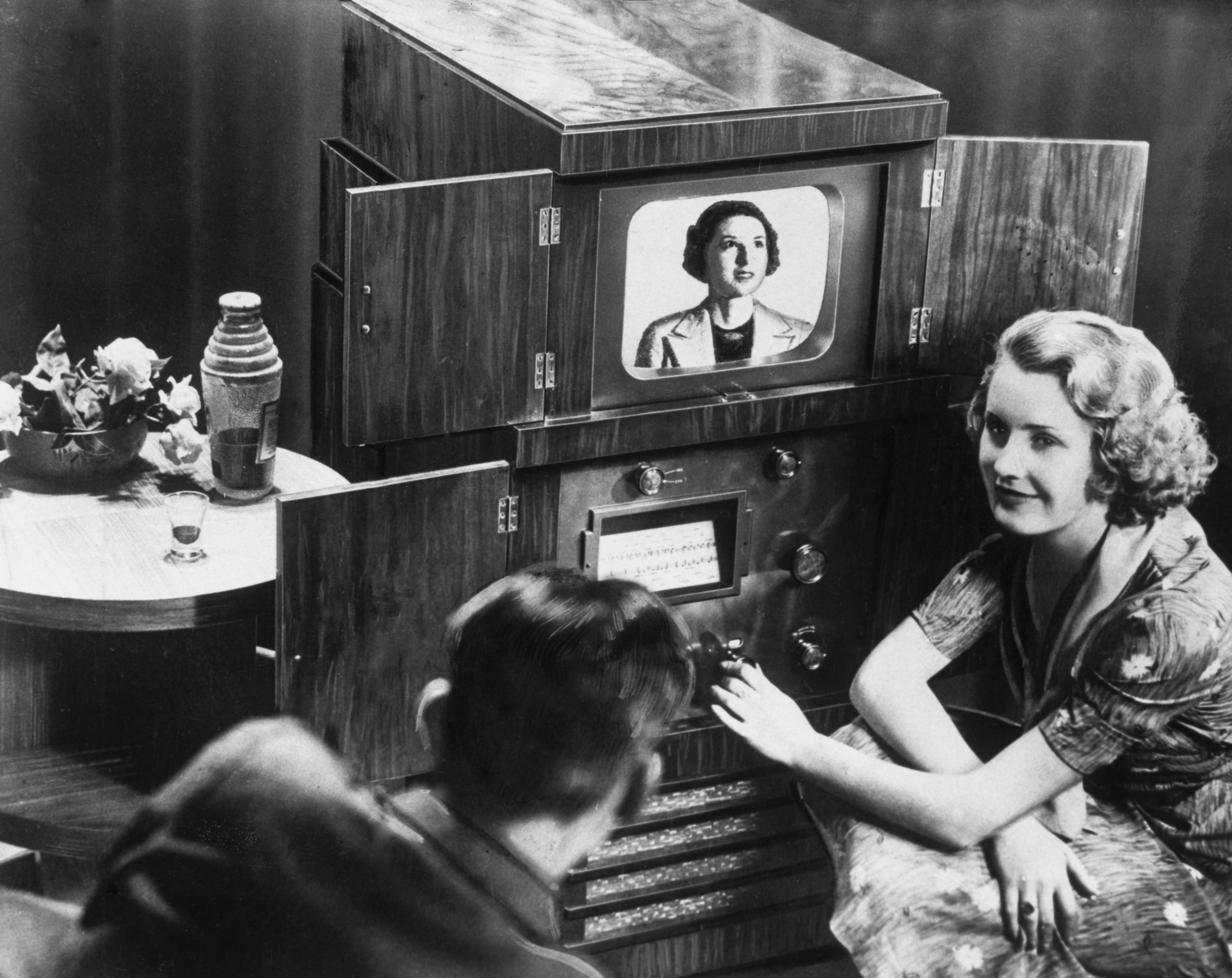Two radical   watching an aboriginal  20th-century tv  acceptable   with a woman's representation  connected  screen, showcasing vintage exertion   successful  a home  setting