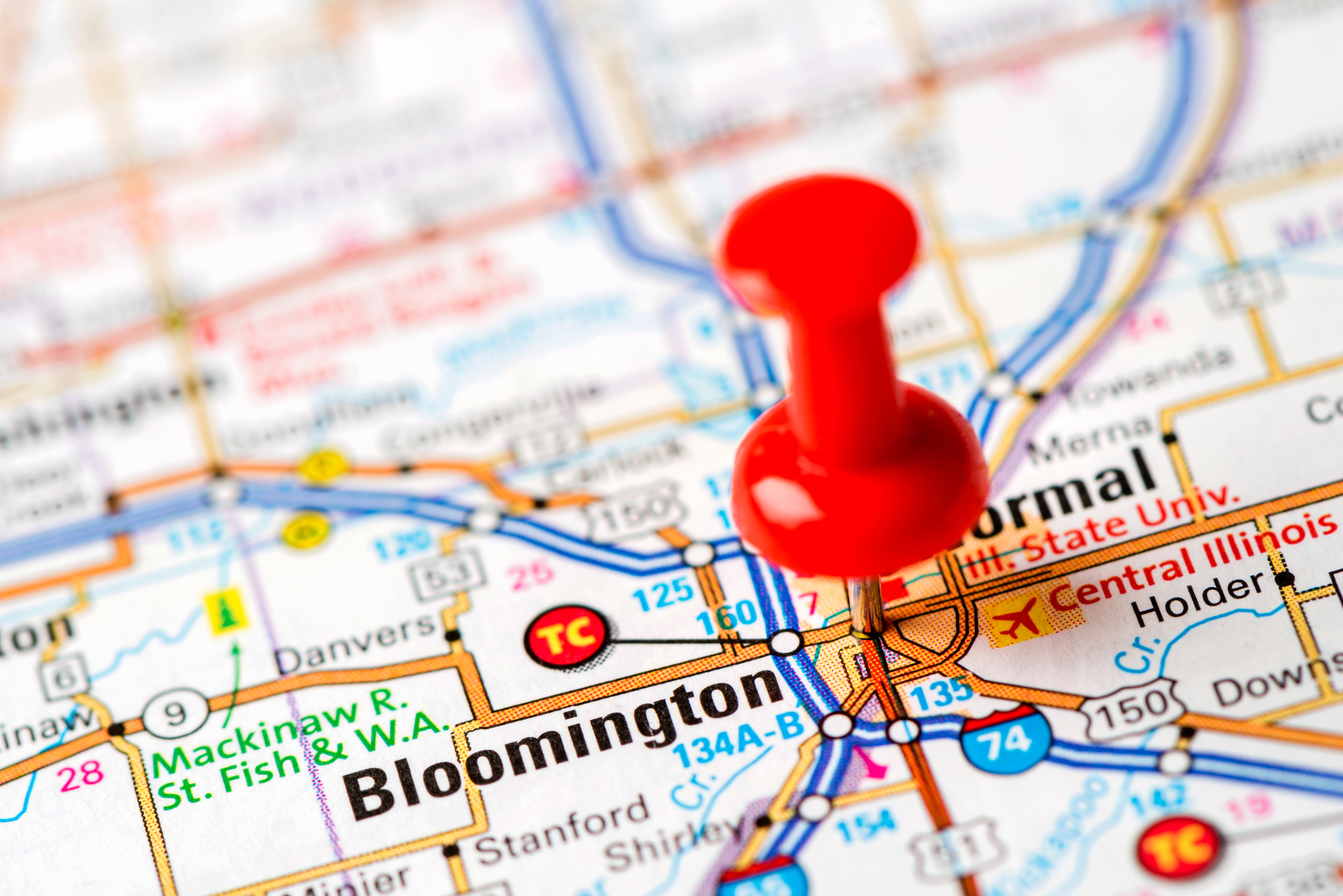 A close-up of a representation  showing Bloomington, Illinois, with a reddish  pushpin marking the location. Nearby cities and way   numbers are visible