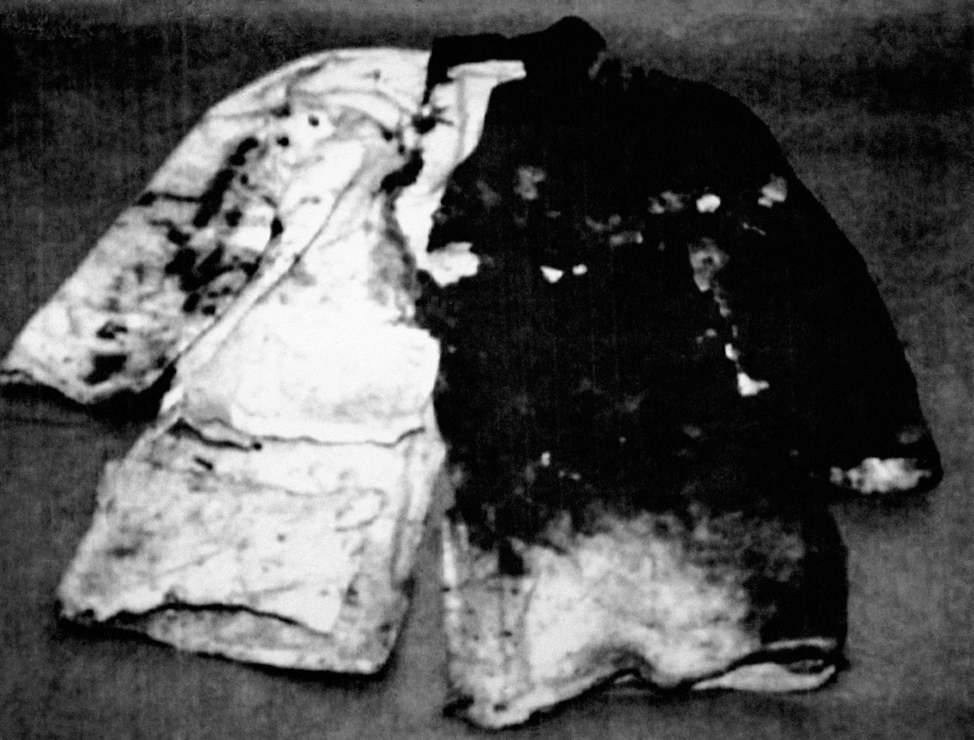 Two fire-damaged jackets, 1  airy  and 1  dark, partially burned and charred, lying connected  a level  surface