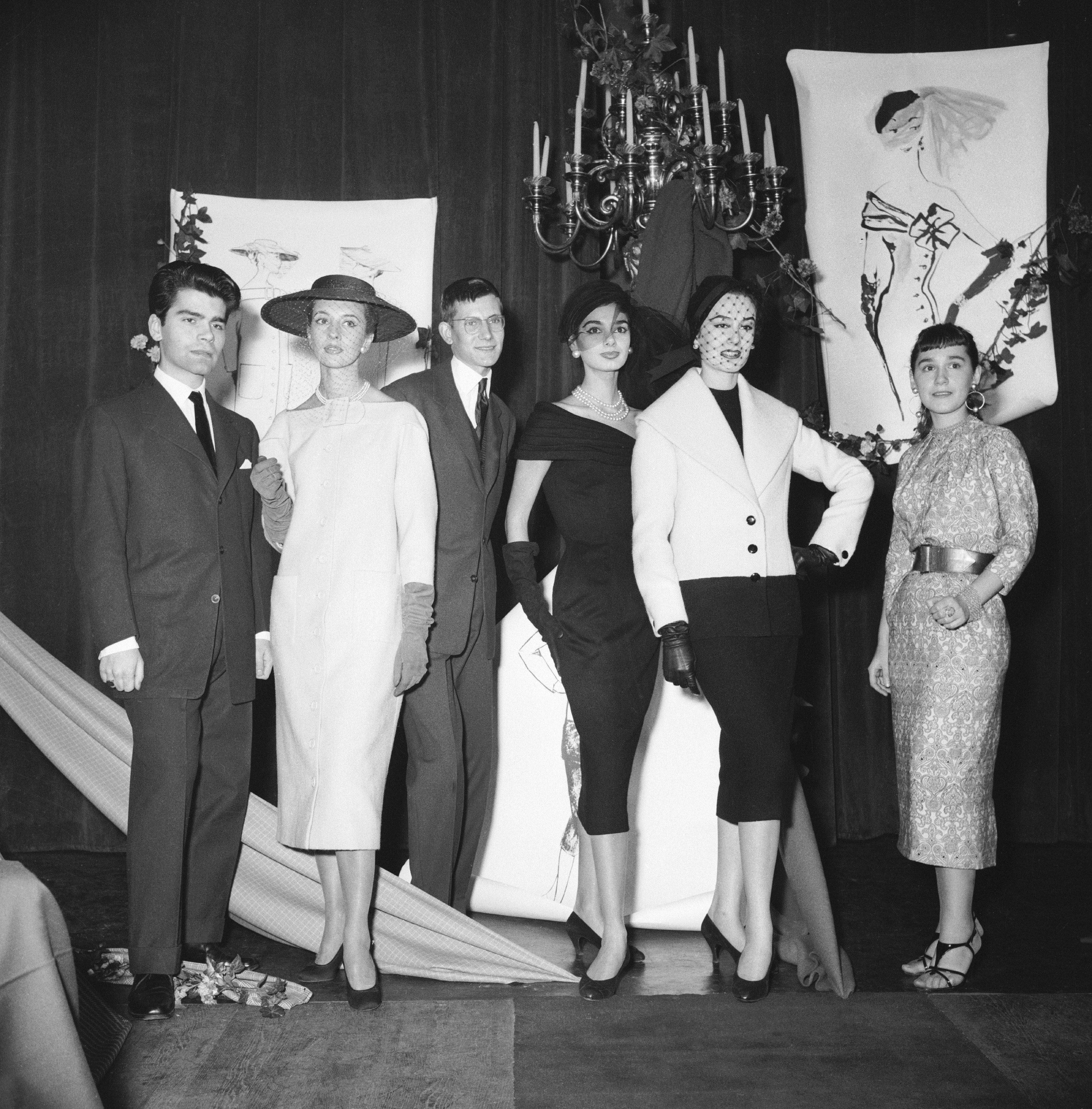 A radical  of individuals successful  1950s fashion, featuring tailored suits, elegant dresses, and hats, posed successful  beforehand   of manner  illustrations