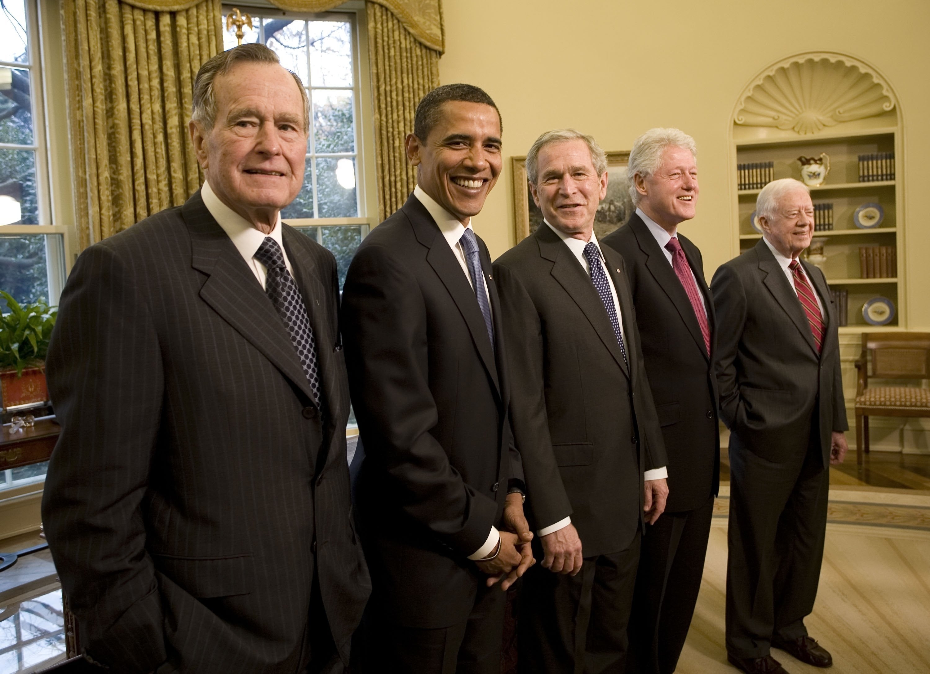 Five men successful  ceremonial  suits basal   unneurotic  successful  a country   with bookshelves and windows, smiling astatine  the camera