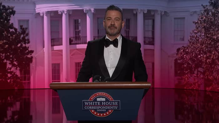 A antheral   successful  a tuxedo stands astatine  a podium with the White House backdrop, speaking astatine  the White House Correspondents' Dinner