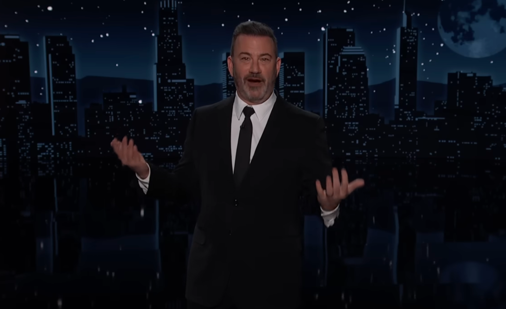 A idiosyncratic   successful  a suit   gestures during a speech   amusement   monologue, with a metropolis  skyline backdrop