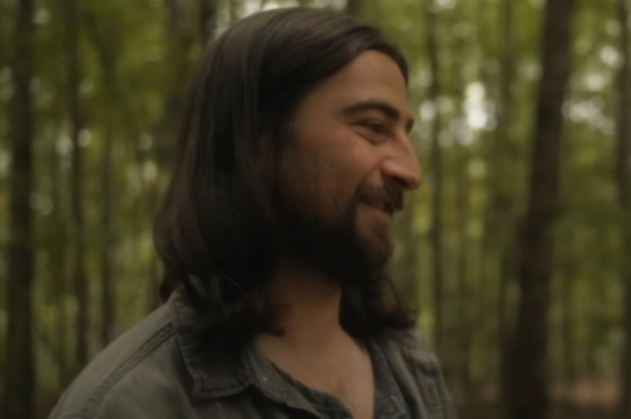 Noah Kahan smiling in the forest in a music video