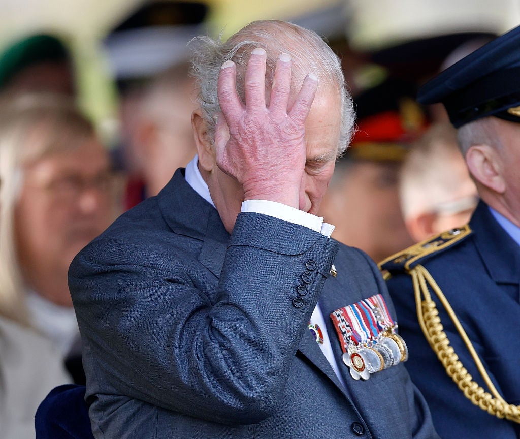 En mann i militæruniform med medaljer berører pannen hans, muligens i et øyeblikks ettertanke, på et formelt utendørsarrangement