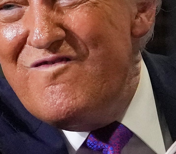 Et nærbilde av Trumps hånd som justerer mikrofonen, den er dekket av sminke og virker hoven