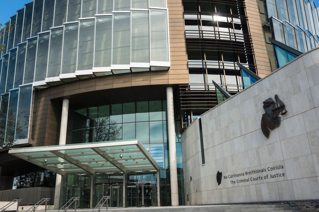 Modern courthouse exterior with solid  facade, metallic  accents, and a salient  entrance. "The Criminal Courts of Justice" is disposable   connected  the building