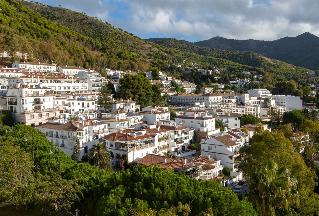 Hillside colony   with achromatic  buildings and terracotta roofs, surrounded by lush greenery and mountains successful  the background