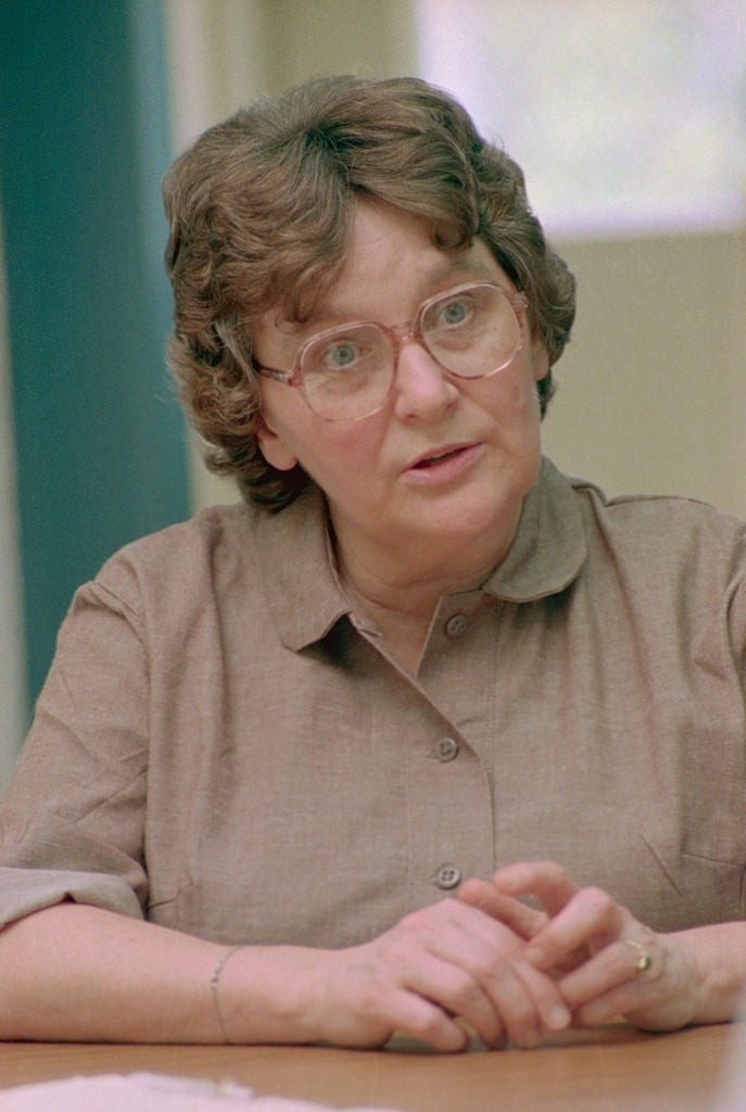 A idiosyncratic   with curly hairsbreadth  and glasses appears engaged successful  conversation, wearing a button-up garment  portion    seated astatine  a table