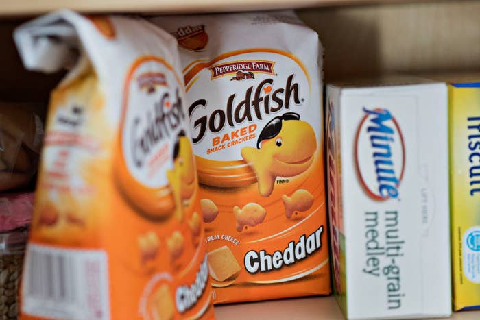 Goldfish Cheddar snack bags connected  a pantry support  adjacent  to boxes of antithetic  foods
