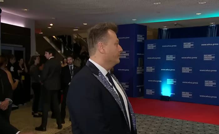 Unidentified idiosyncratic   successful  a tuxedo connected  a reddish  carpet astatine  a ceremonial  event, with a backdrop featuring "WHCA" logos