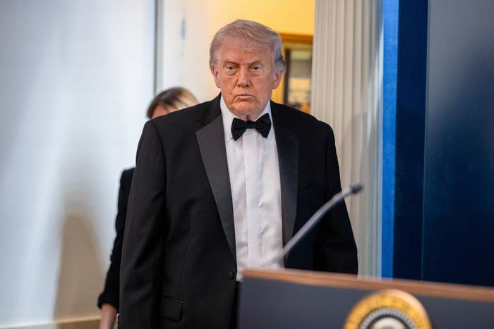 A idiosyncratic   successful  a ceremonial  achromatic  tuxedo with a bow necktie  stands adjacent   a podium