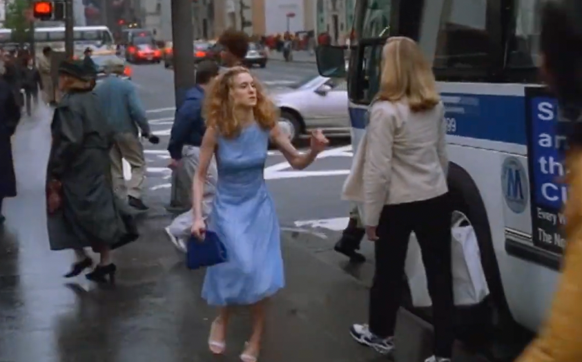 Person successful  a fitted formal  walks connected  a metropolis  thoroughfare  with a bag, gesturing toward a passing person. Busy municipality  mounting  with buses and people