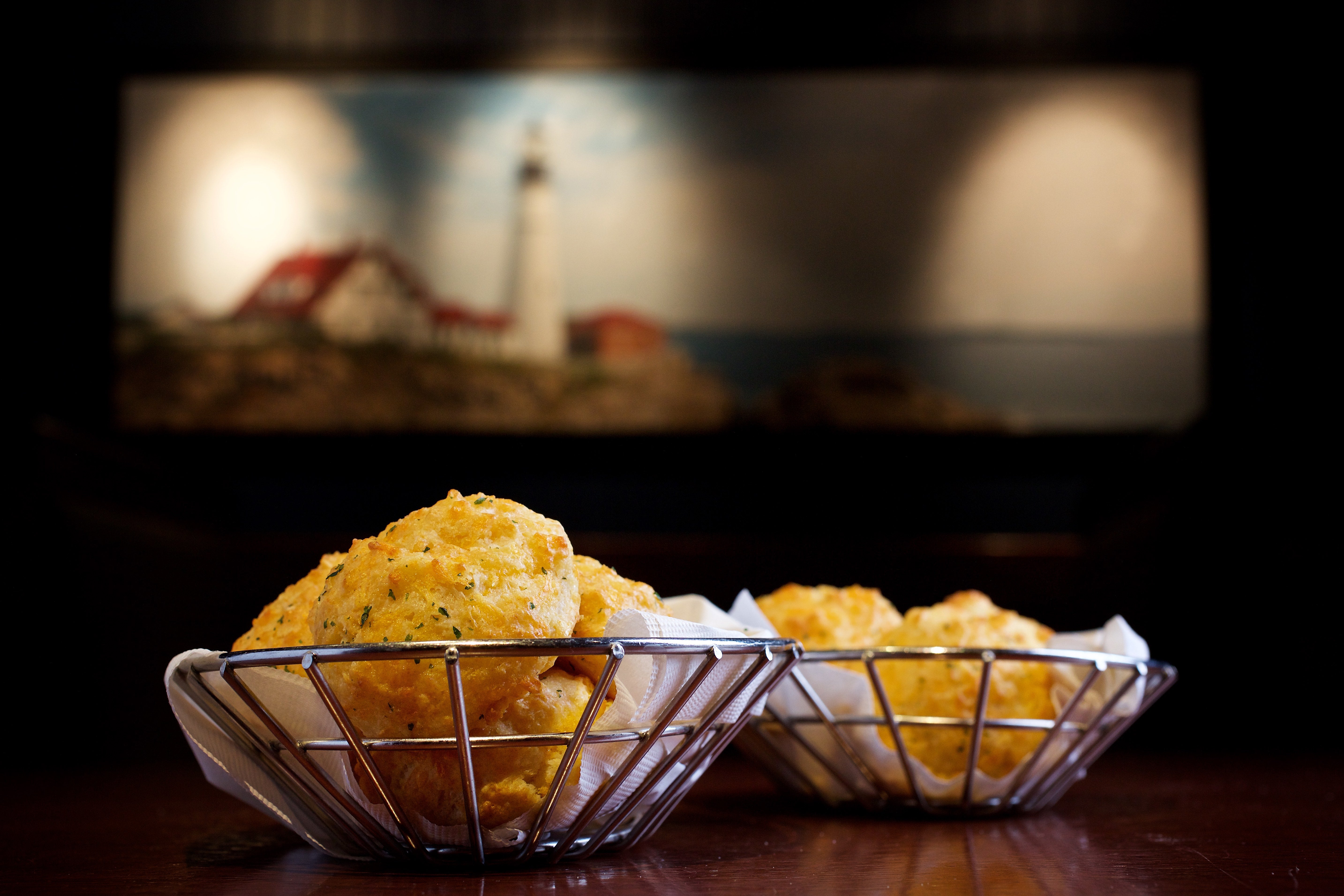 Baskets of aureate  biscuits connected  a table, with a blurred lighthouse coating  successful  the background