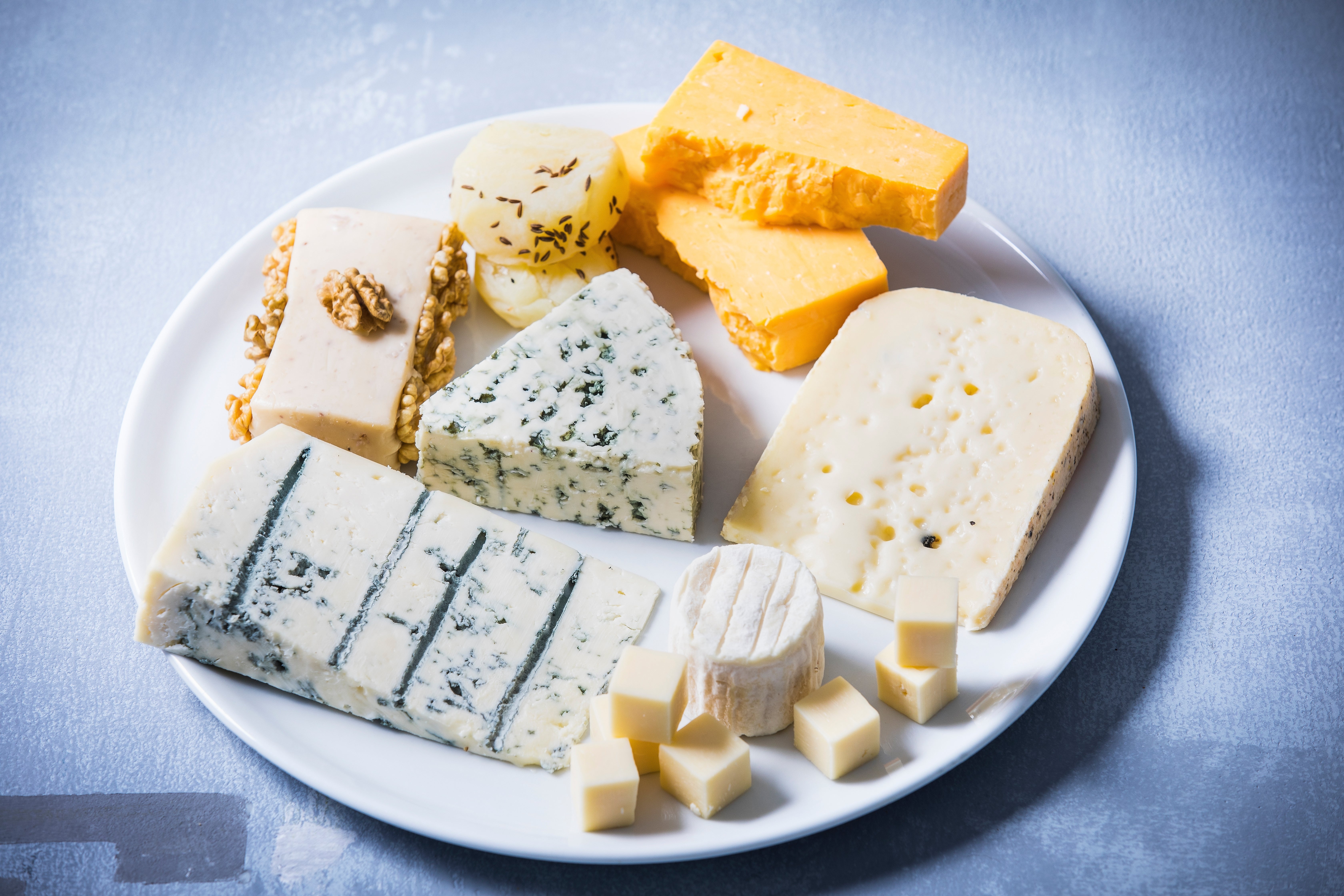 A sheet  of assorted cheeses, including bluish  cheese, brie, and cheddar, arranged for a health-related article