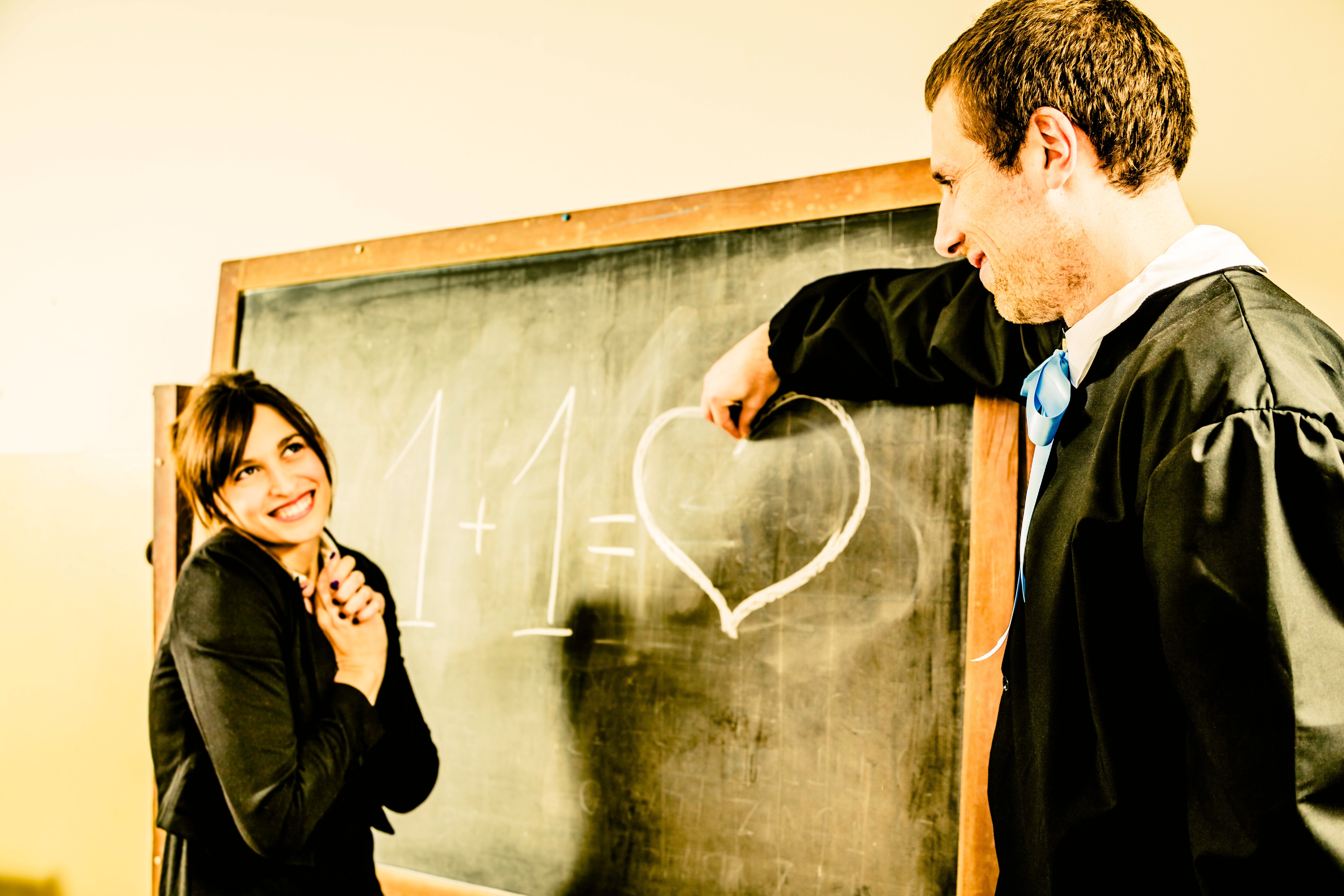 Woman smiles astatine  antheral   successful  gown drafting  "1 + 1 = ♥" connected  chalkboard, symbolizing emotion  oregon  partnership