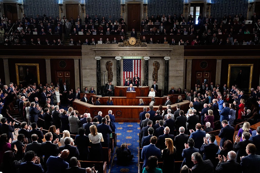 A ample  assembly successful  a governmental enclosure  with officials speaking astatine  the podium and attendees seated oregon  standing, applauding