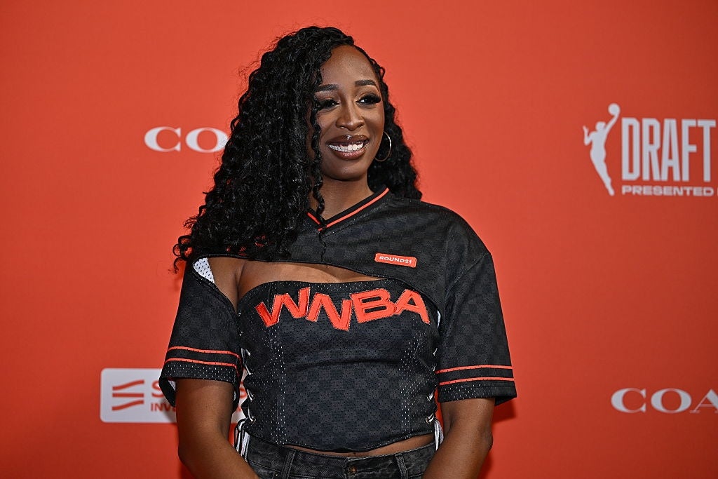 Person på rød løper iført en sporty topp med WNBA-tema med utskjæringer og flettet frisyre