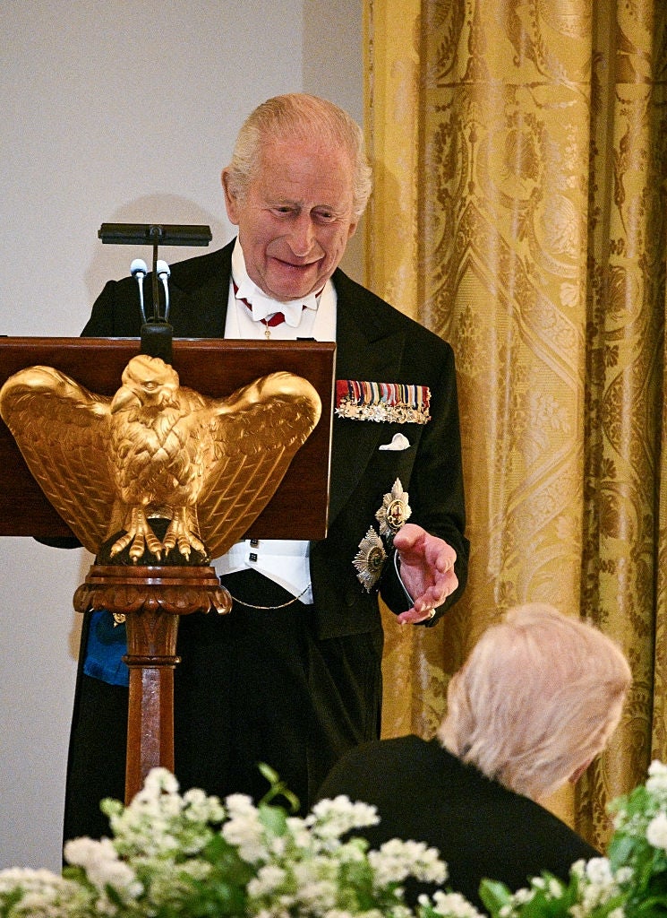 A distinguished older antheral   successful  ceremonial  attire speaks astatine  a podium adorned with an eagle sculpture, addressing an assemblage  astatine  an elegant event