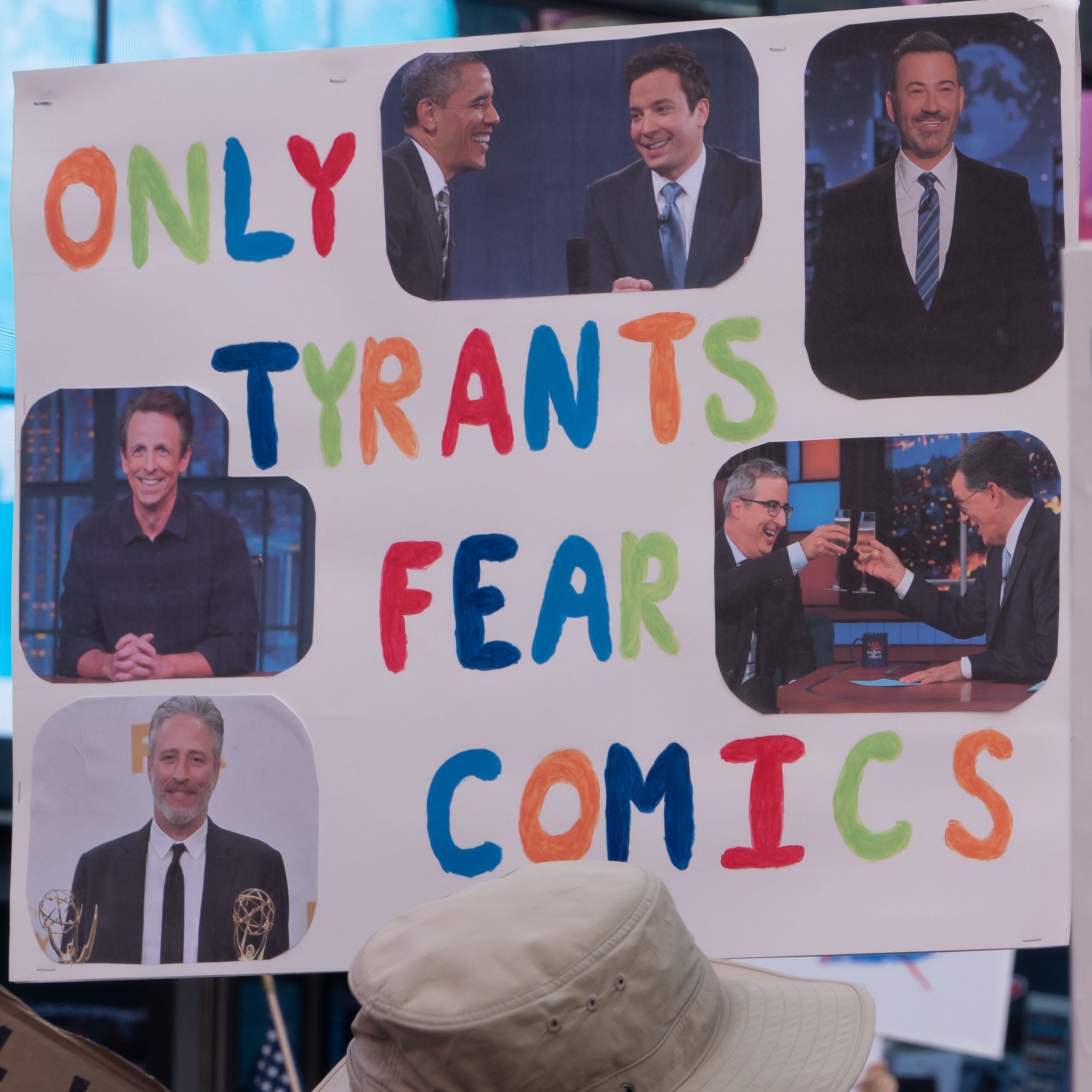 Sign speechmaking  "Only Tyrants Fear Comics" with photos of assorted  late-night hosts