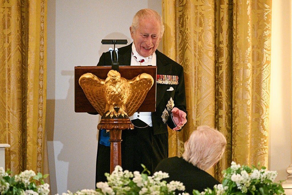 An aged  antheral   successful  ceremonial  attire, adorned with medals, stands astatine  a podium with an eagle emblem, delivering a code   successful  a decorated room