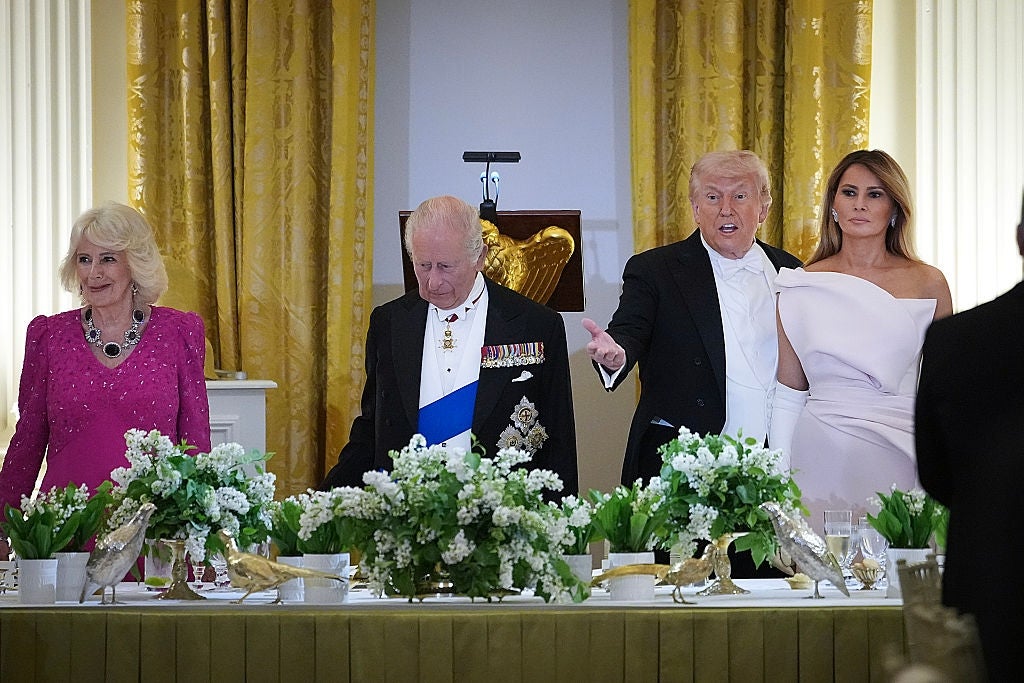 Four radical   basal   down  a decorated banquet table; 1  gestures portion    the others smile. Formal attire includes a gown and a subject   uniform
